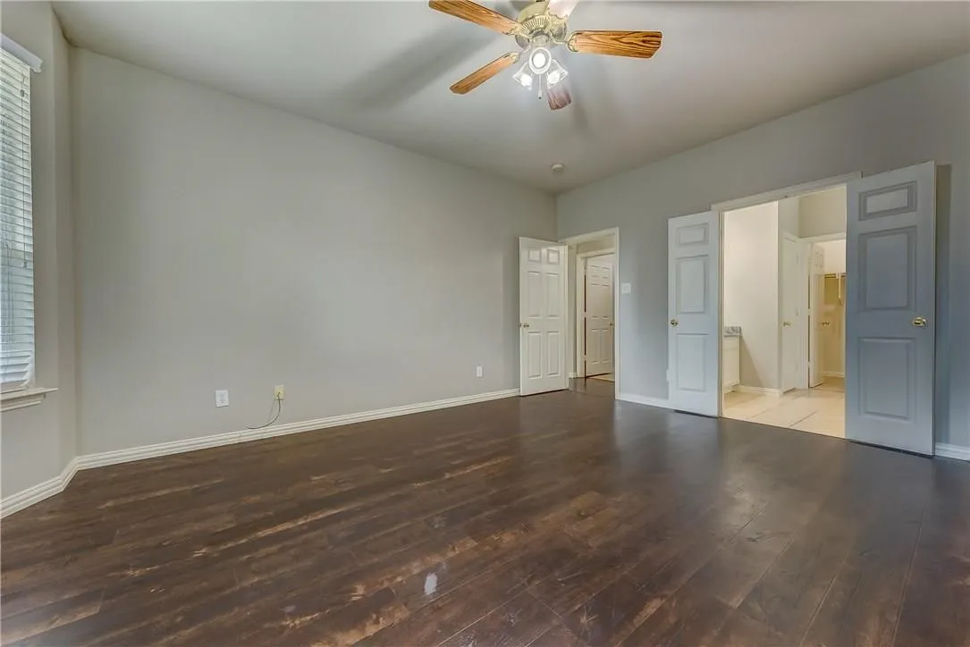 Unfurnished bedroom featuring ensuite bath, ceiling fan, and hardwood / wood-style floors