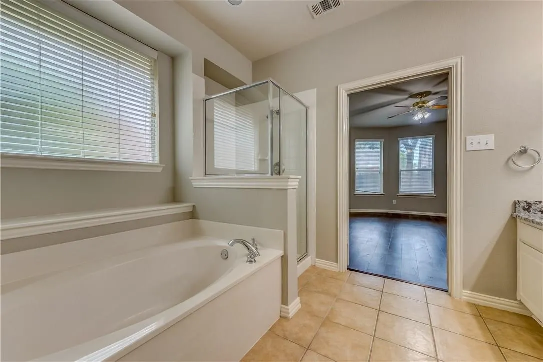 Bathroom featuring tile flooring, ceiling fan, vanity, and plus walk in shower