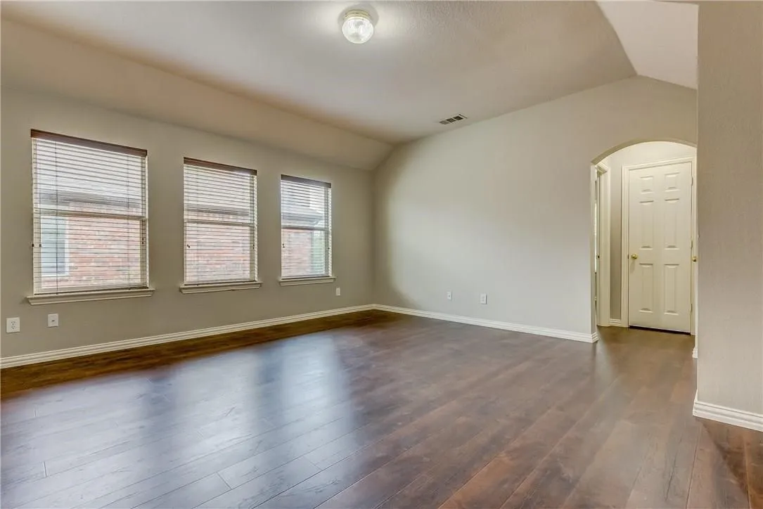 Unfurnished room with dark wood-type flooring and lofted ceiling