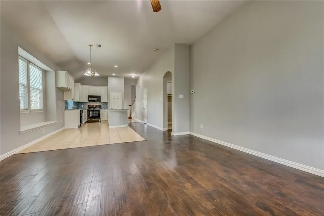 Unfurnished living room featuring light tile floors and an inviting chandelier
