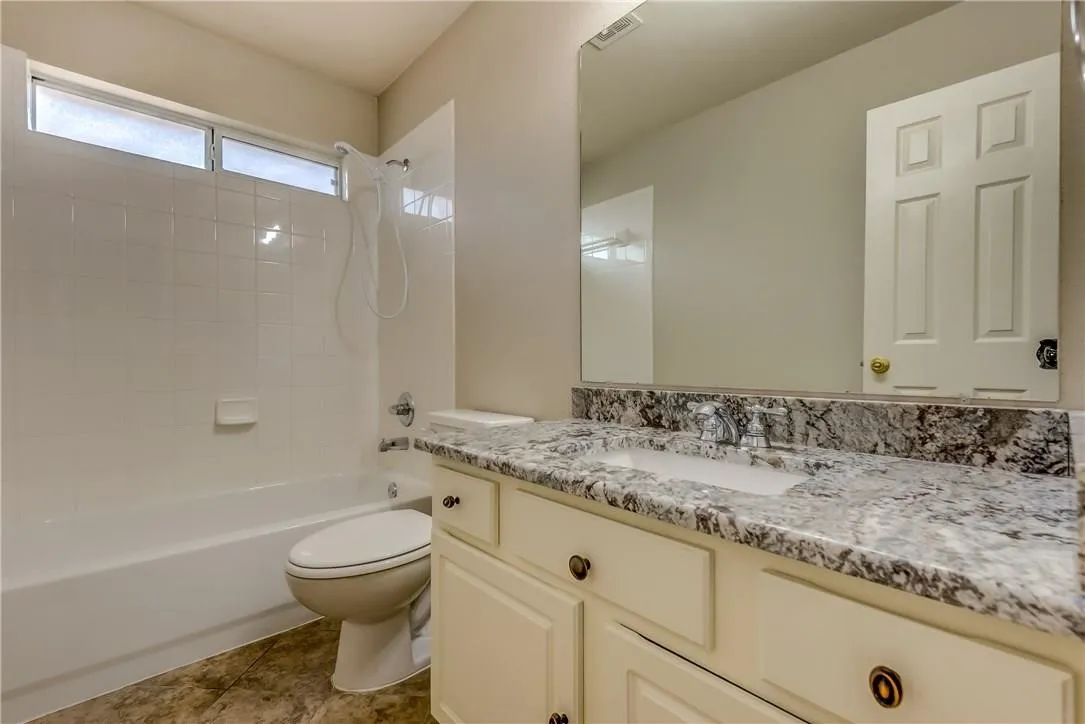 Full bathroom featuring toilet, vanity with extensive cabinet space, tiled shower / bath, and tile flooring