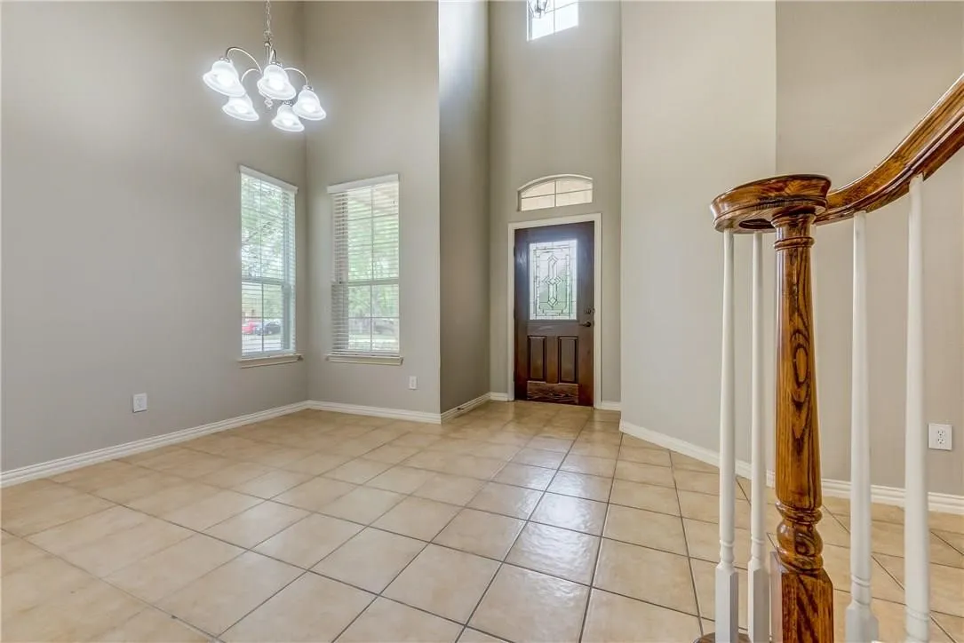 Foyer entrance with a notable chandelier, a high ceiling, and light tile floors