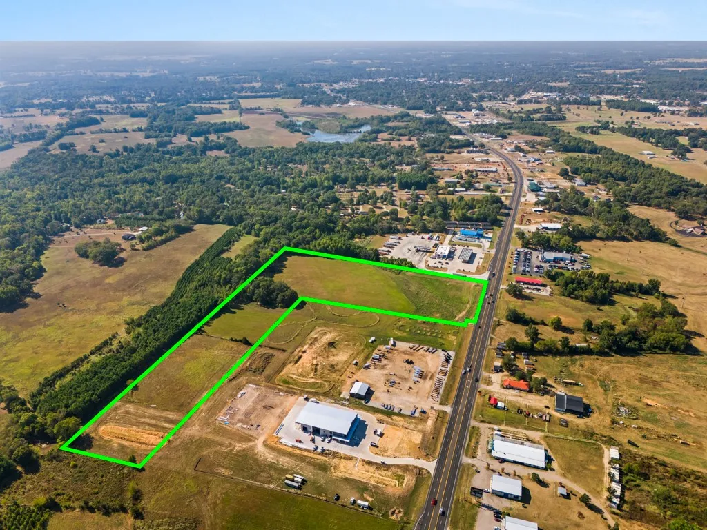 Expansive parcel featuring open fields, mature tree lines, and direct highway frontage