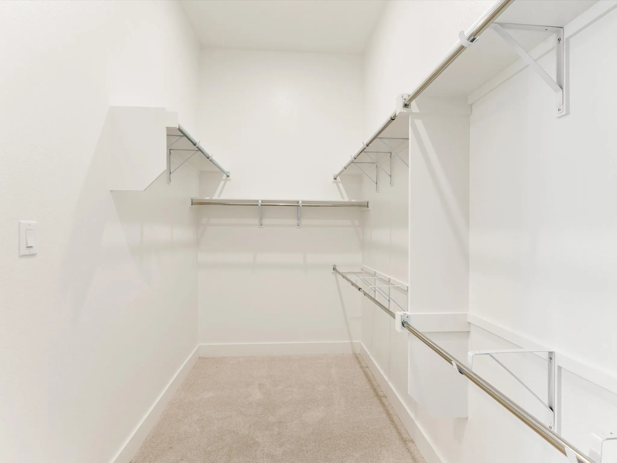 Built-in shelving and hanging rods in a white finish, complemented by light-toned carpeting