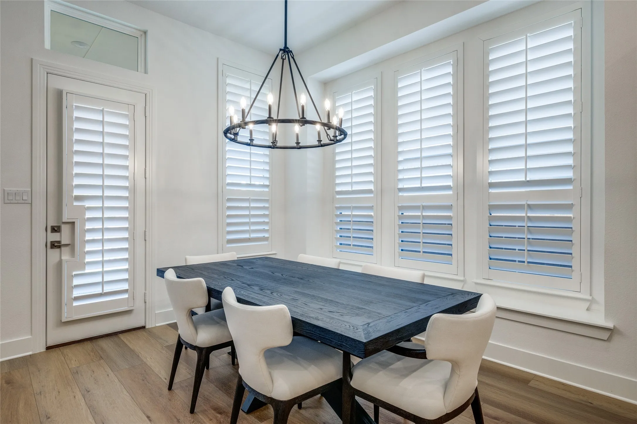Wood-finish flooring, white walls, and a contemporary chandelier