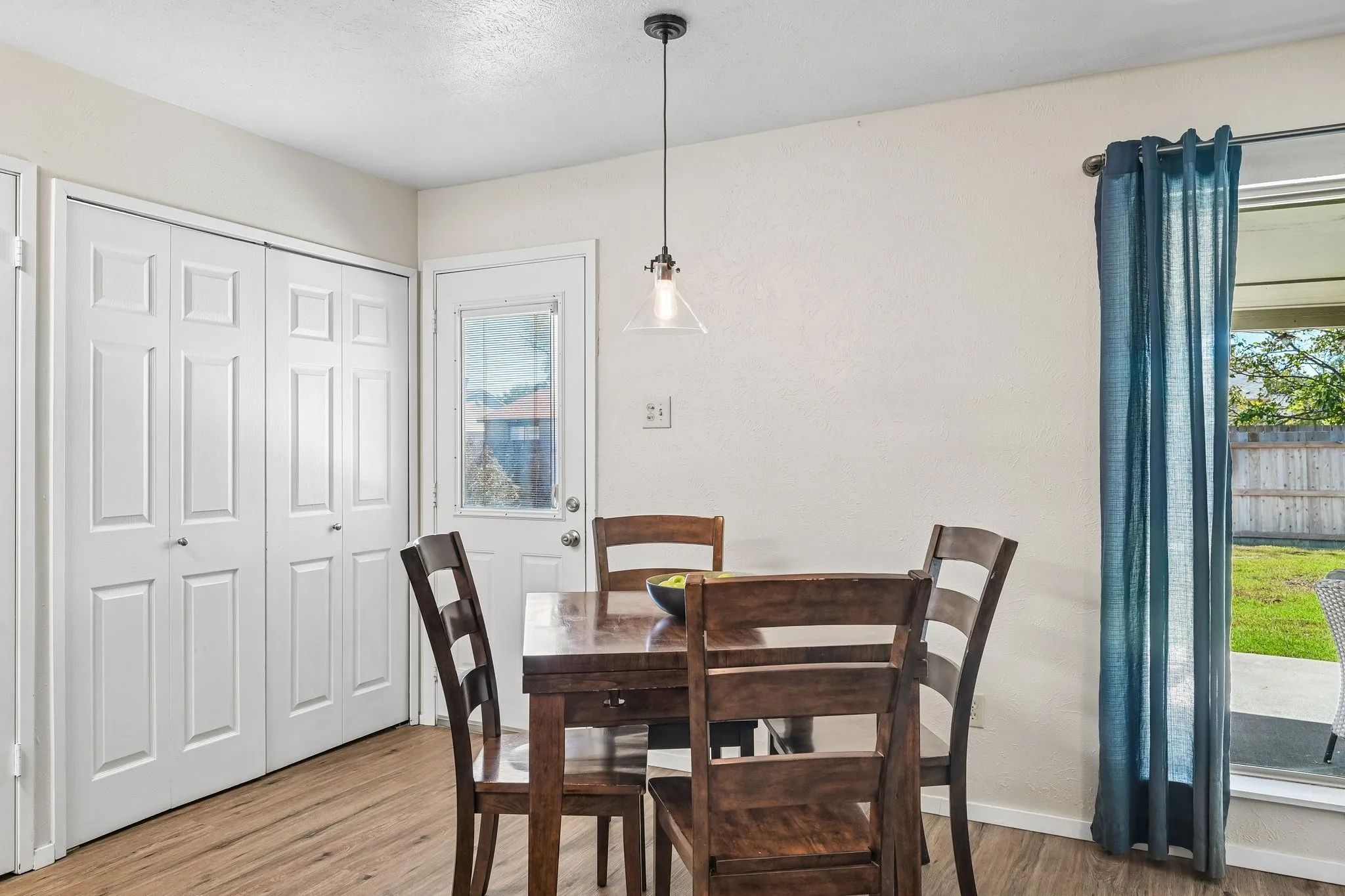 Wood-finish flooring, white paneled bifold doors, and a glass-paned exterior door