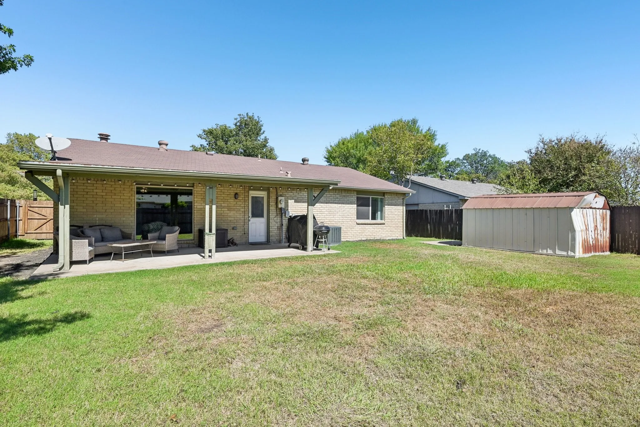 Expansive grassy yard with a covered patio featuring a concrete surface