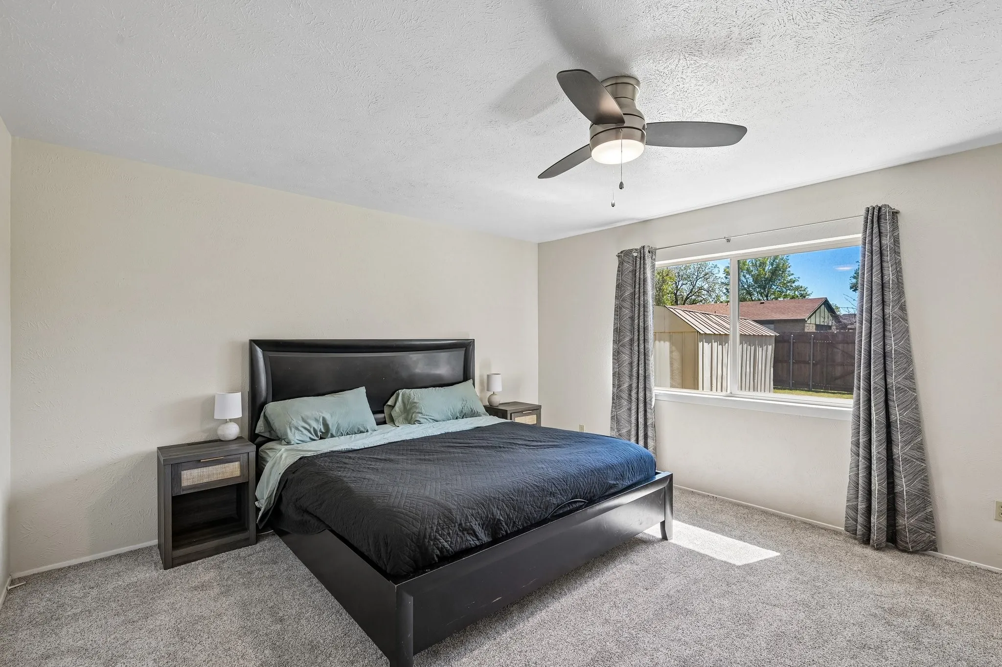 Neutral wall finishes with a ceiling fan, carpeted flooring, and a large window