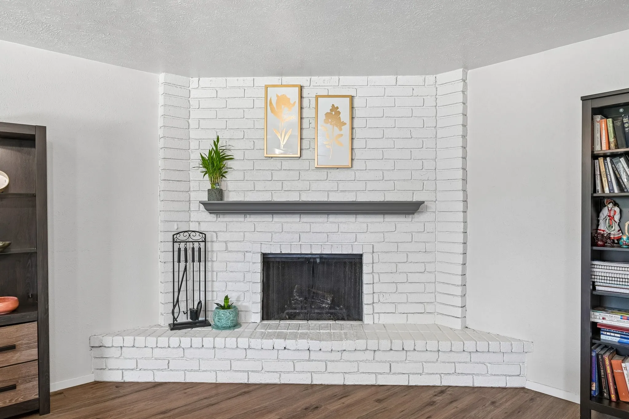 Corner fireplace with a painted brick surround, dark mantel, and a black firebox