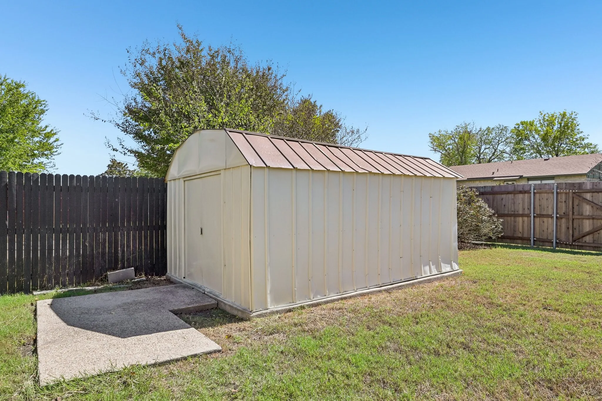 Detached storage shed with a metal roof and concrete pad