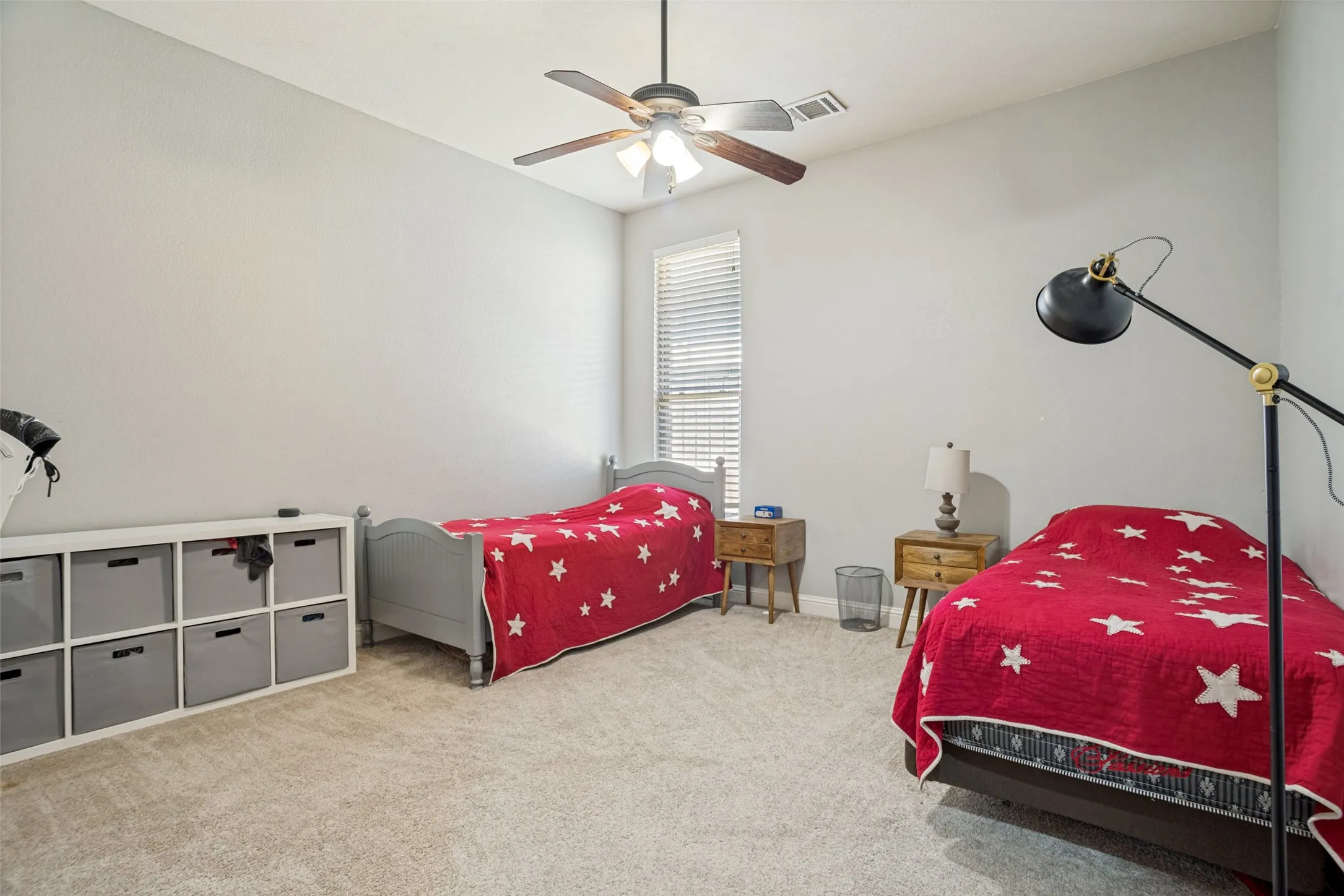 Carpeted room featuring a ceiling fan with integrated lighting and a window with blinds