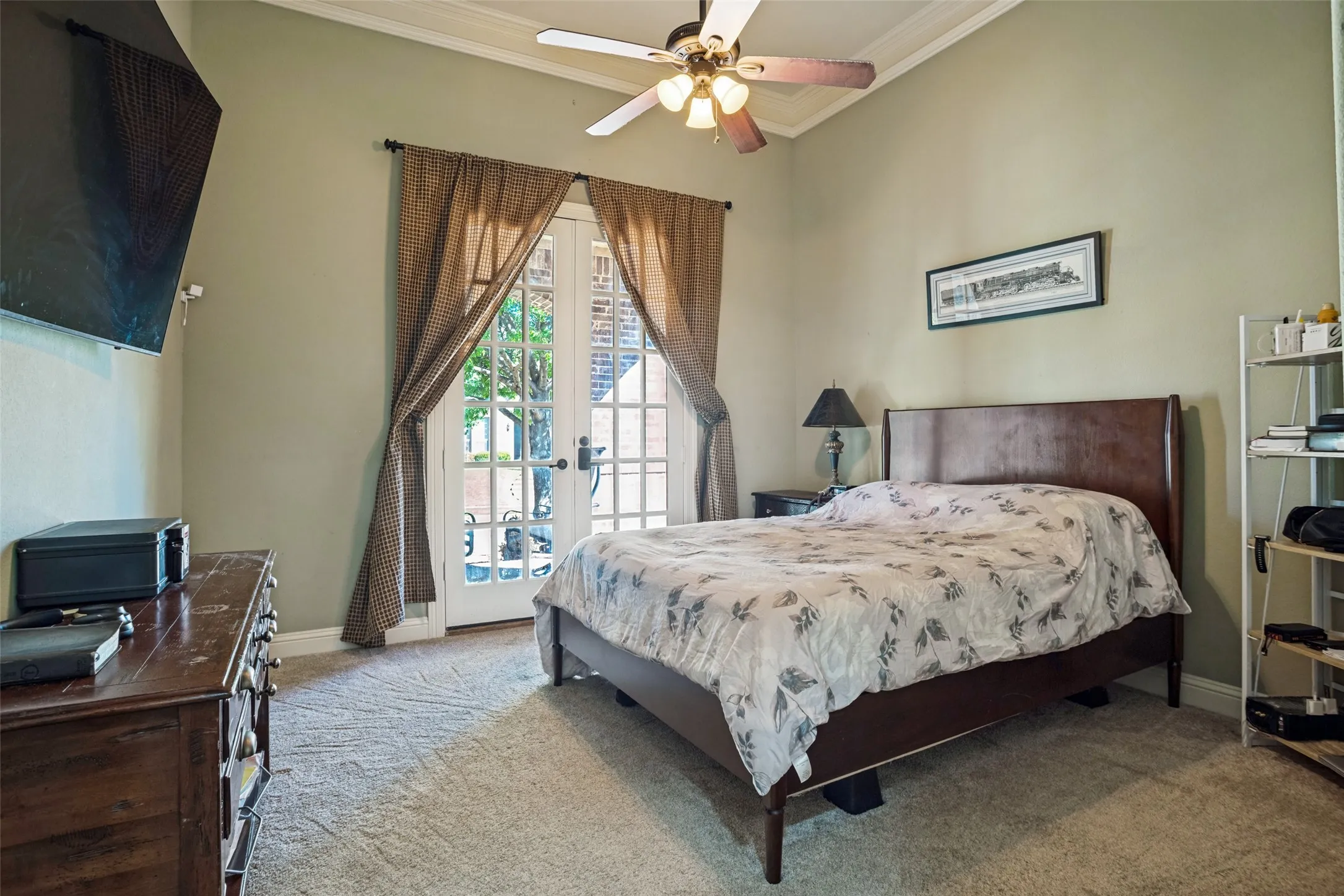 Double French doors, crown molding, wall-mounted television, and carpet flooring