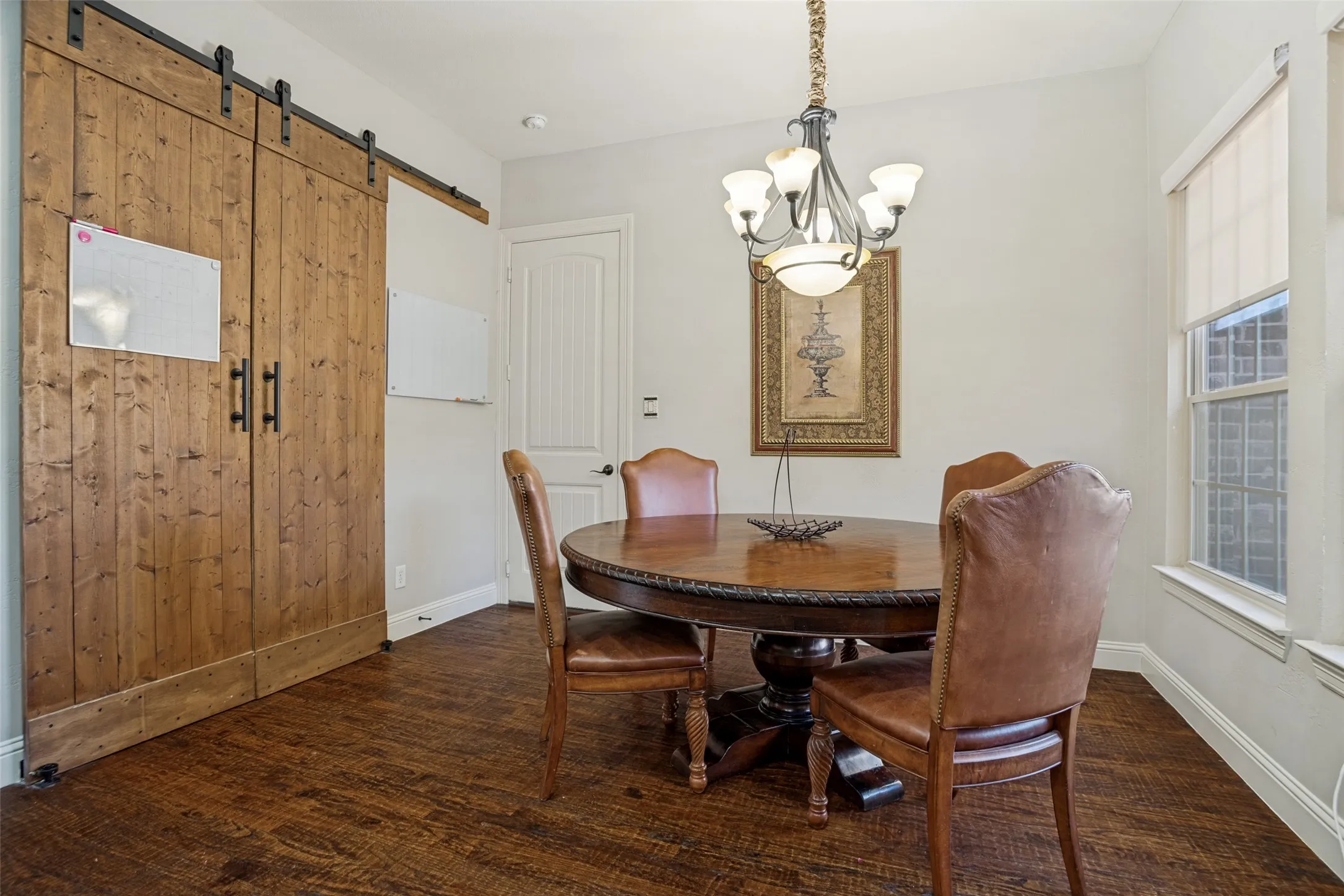 Wood-finish flooring, white walls, and a large window with roller shades