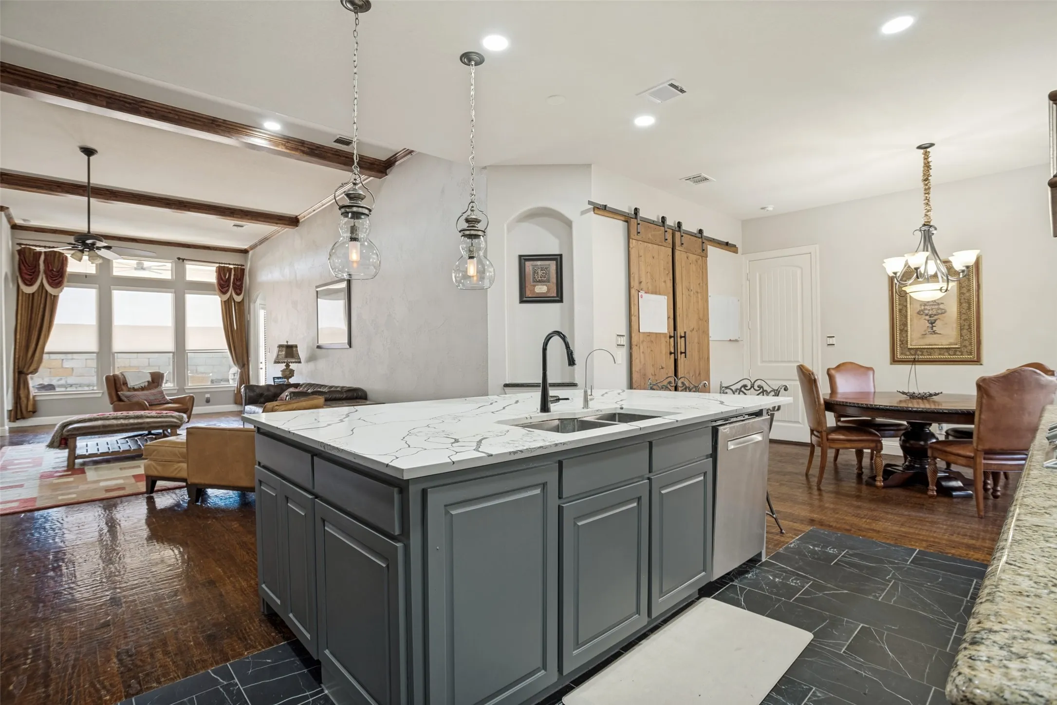 Kitchen island with a white stone countertop, dual basin sink, and gray cabinetry