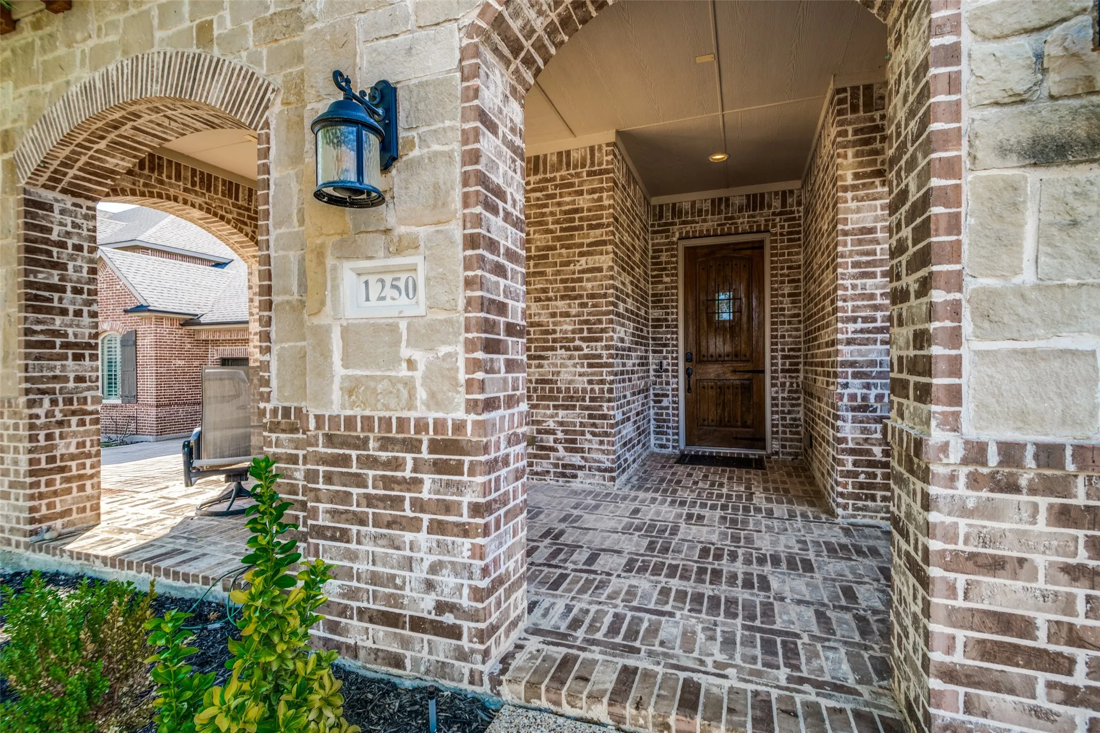 Arched brick entryway featuring a decorative wooden door with iron accents