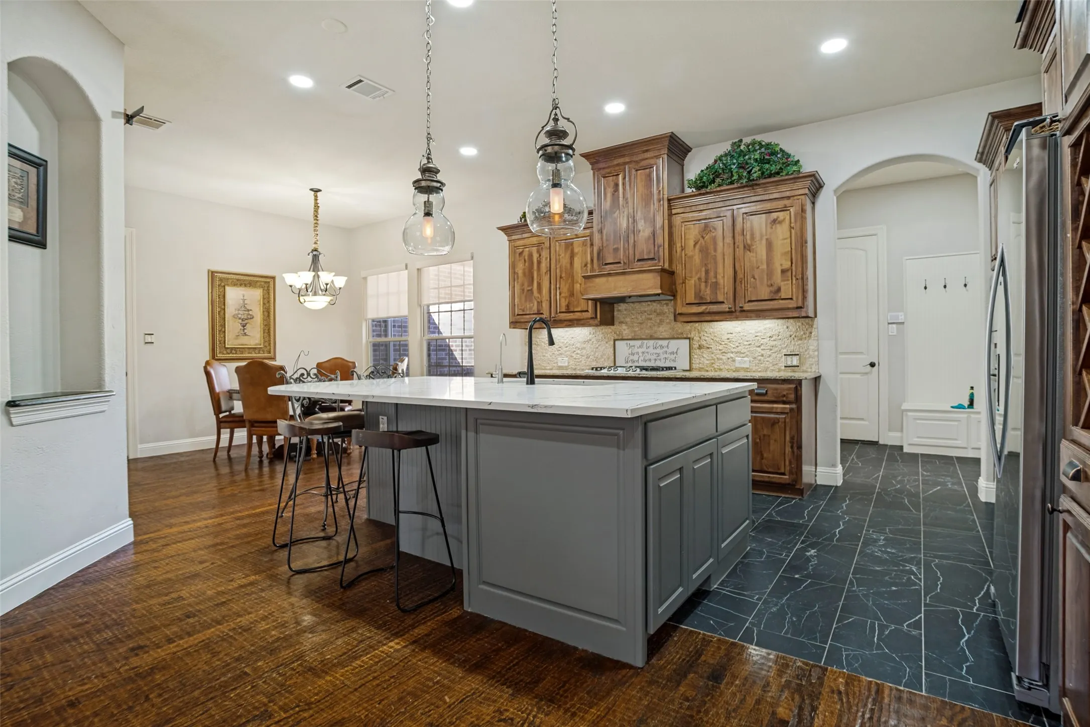Kitchen featuring an island with a light-toned countertop, wood-finish flooring, and dark wood cabinetry