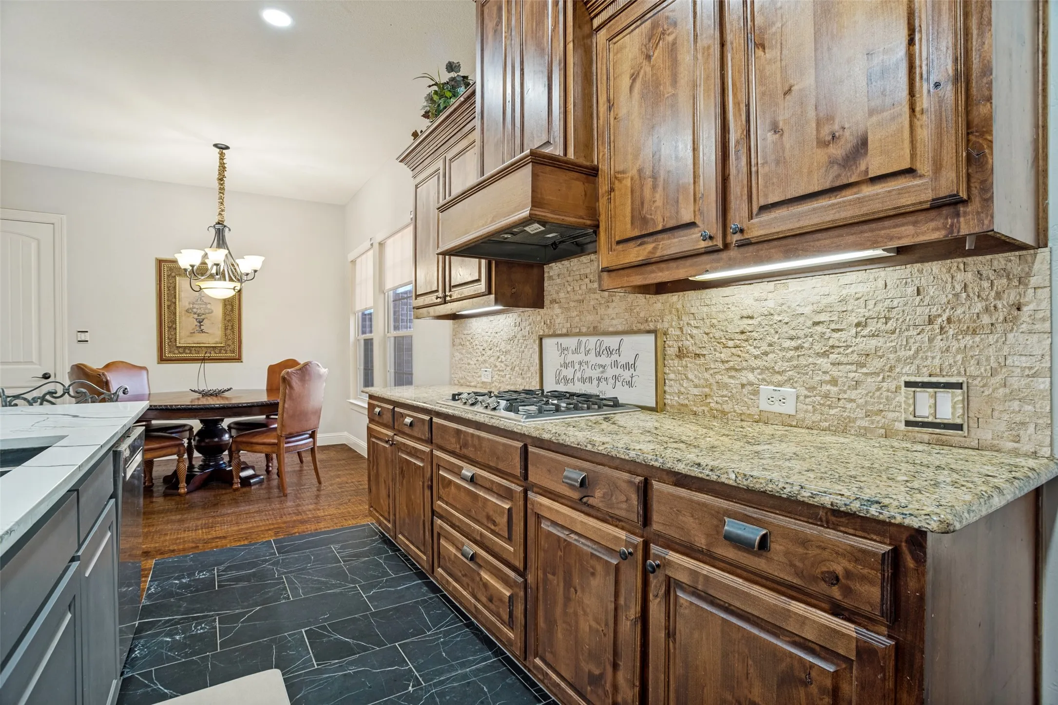 Kitchen with dark wood cabinetry, light-colored textured tile backsplash, and a built-in gas range