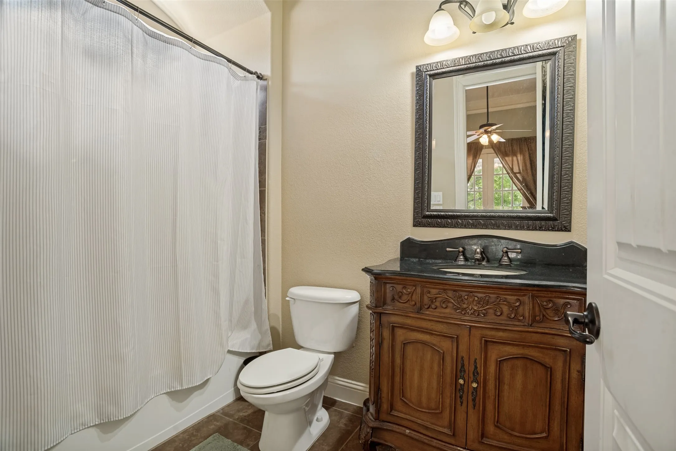 Traditional vanity with carved wood details, a dark countertop, and an undermount sink