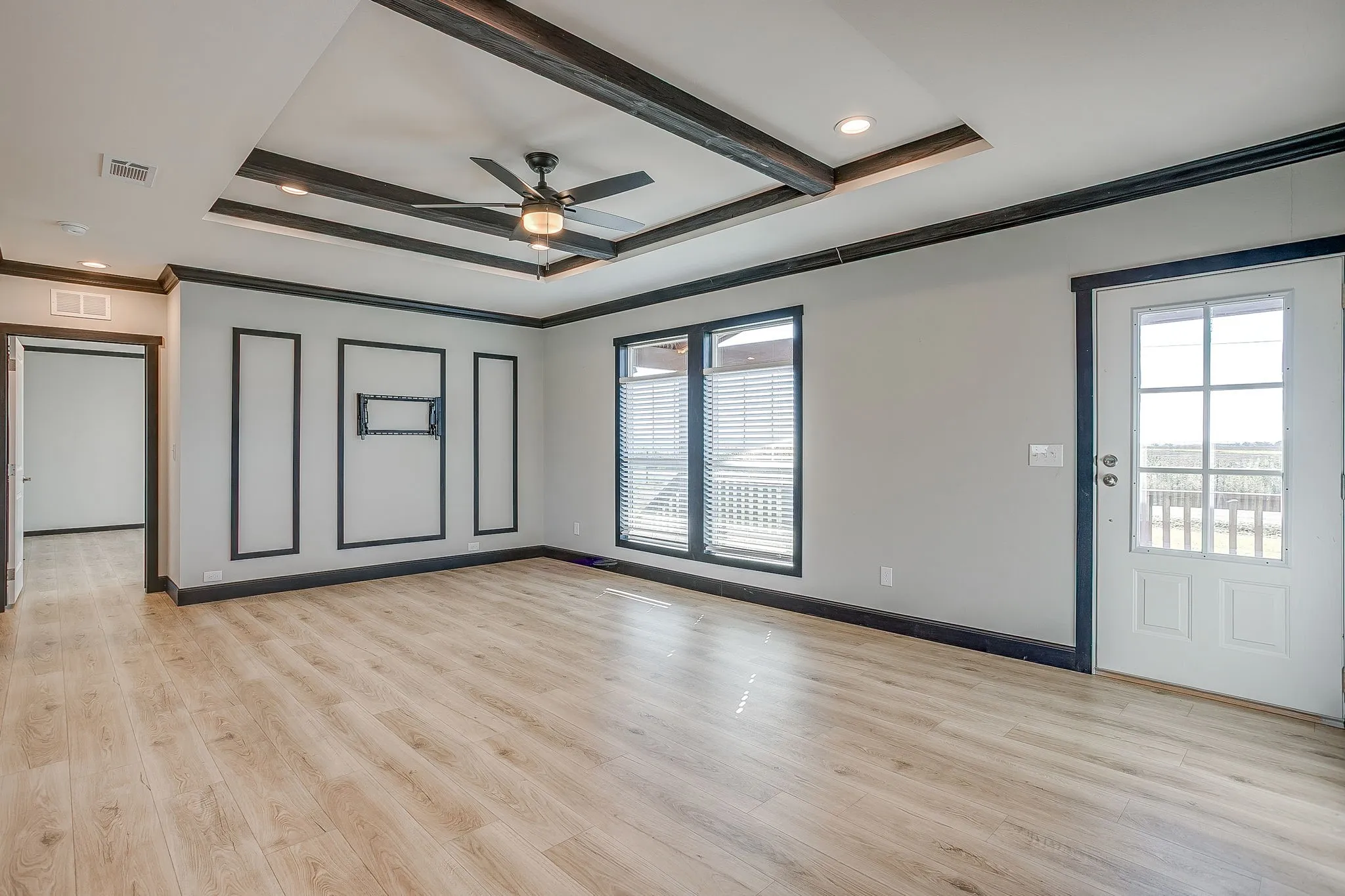 Tray ceiling with decorative beams, ceiling fan, recessed lighting, wood-finish flooring, and a glass-paned exterior door