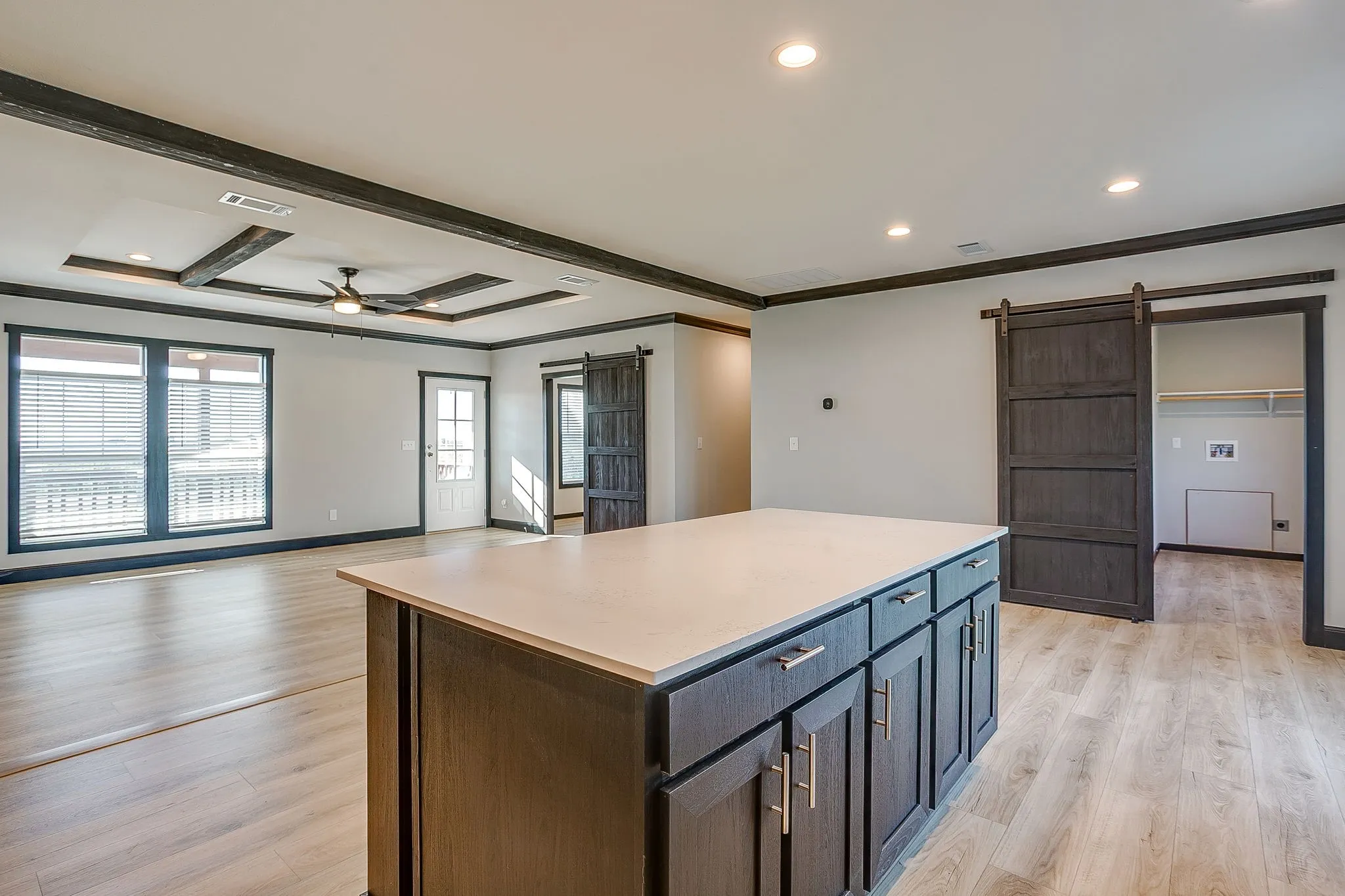 Wood-finish flooring throughout, featuring a kitchen island with white countertop