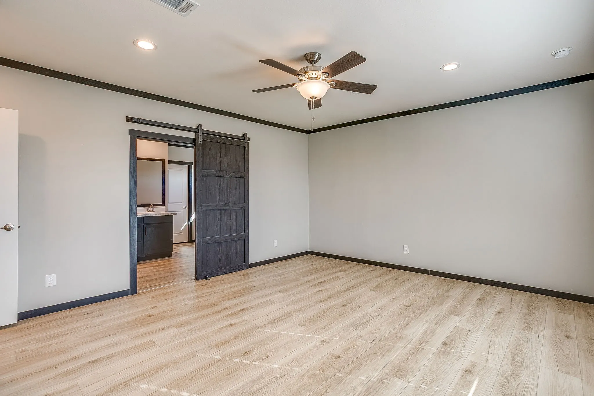 Recessed lighting, wood-finish flooring, ceiling fan, dark trim, and a barn door