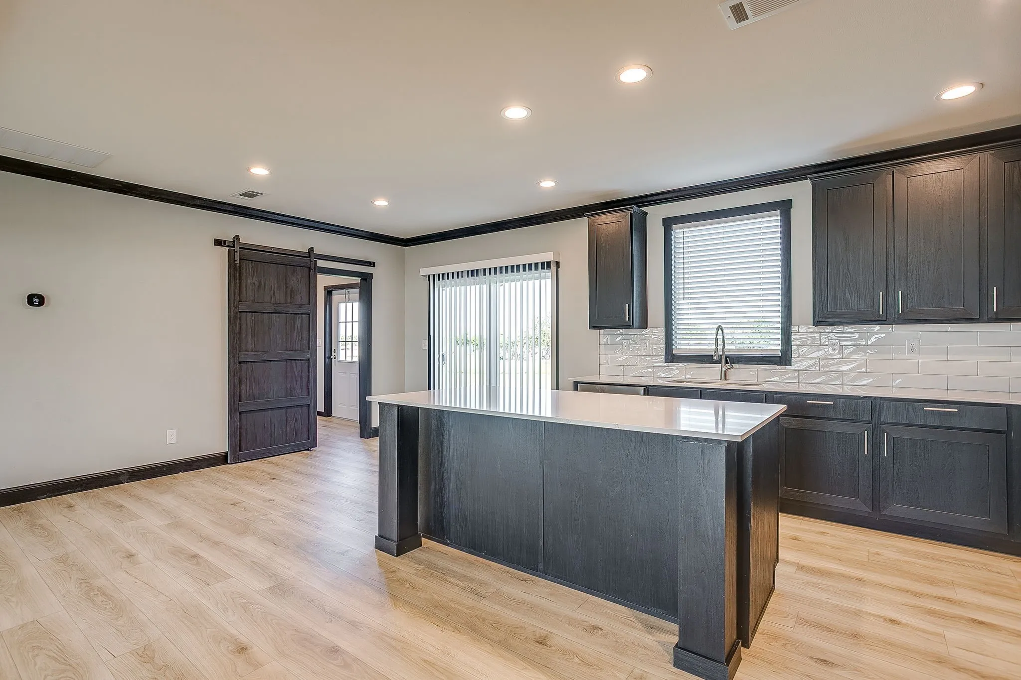 Kitchen featuring dark wood-finish cabinetry, light countertops, subway tile backsplash, and a central island