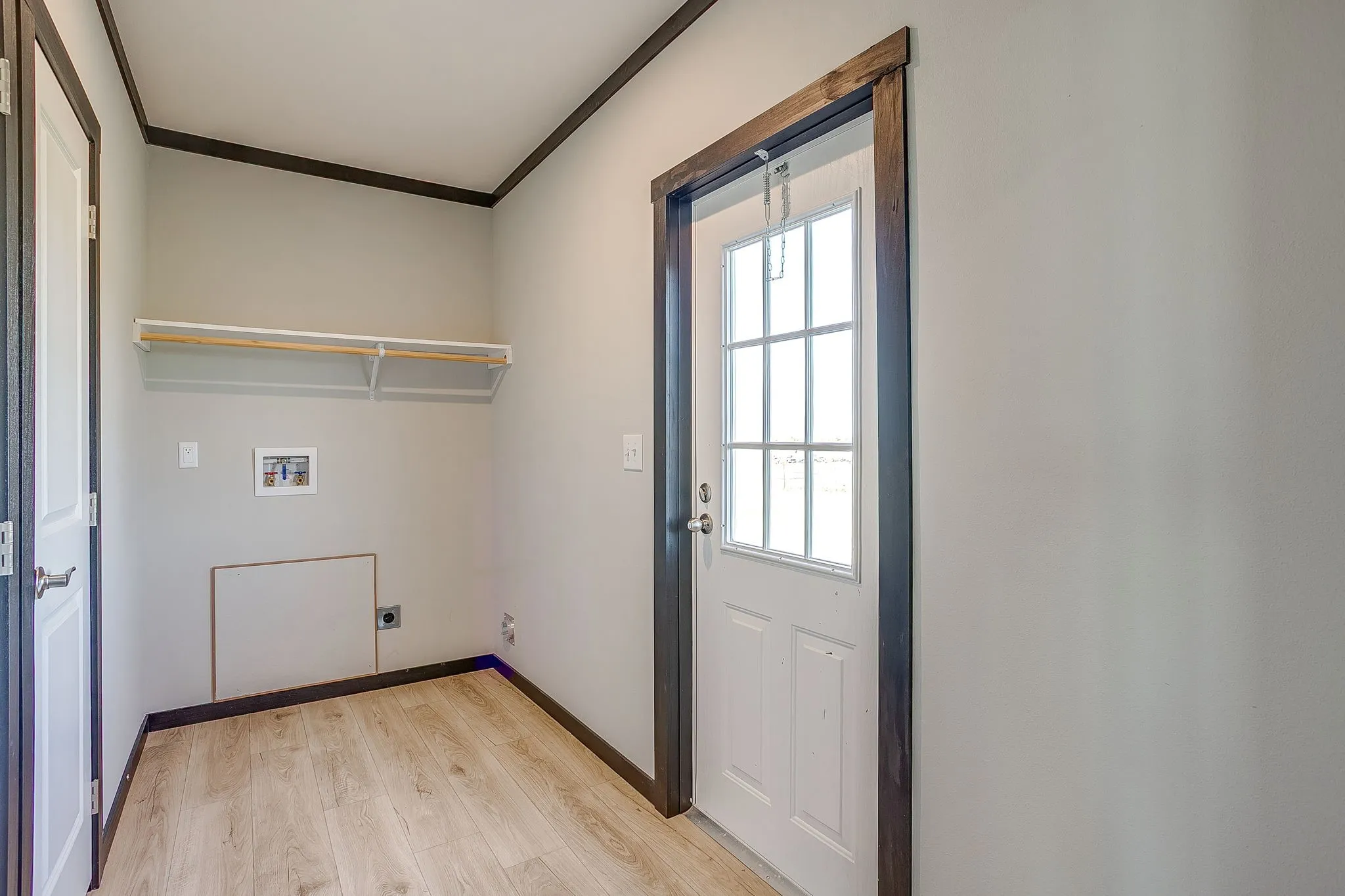Utility space with light wood-finish flooring, white walls, and dark trim