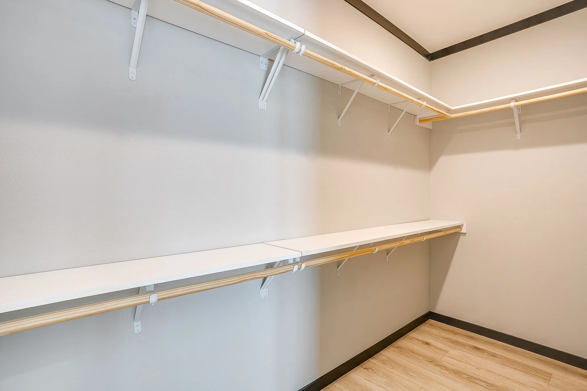 Integrated shelving and hanging rods with wood-finish flooring and dark trim