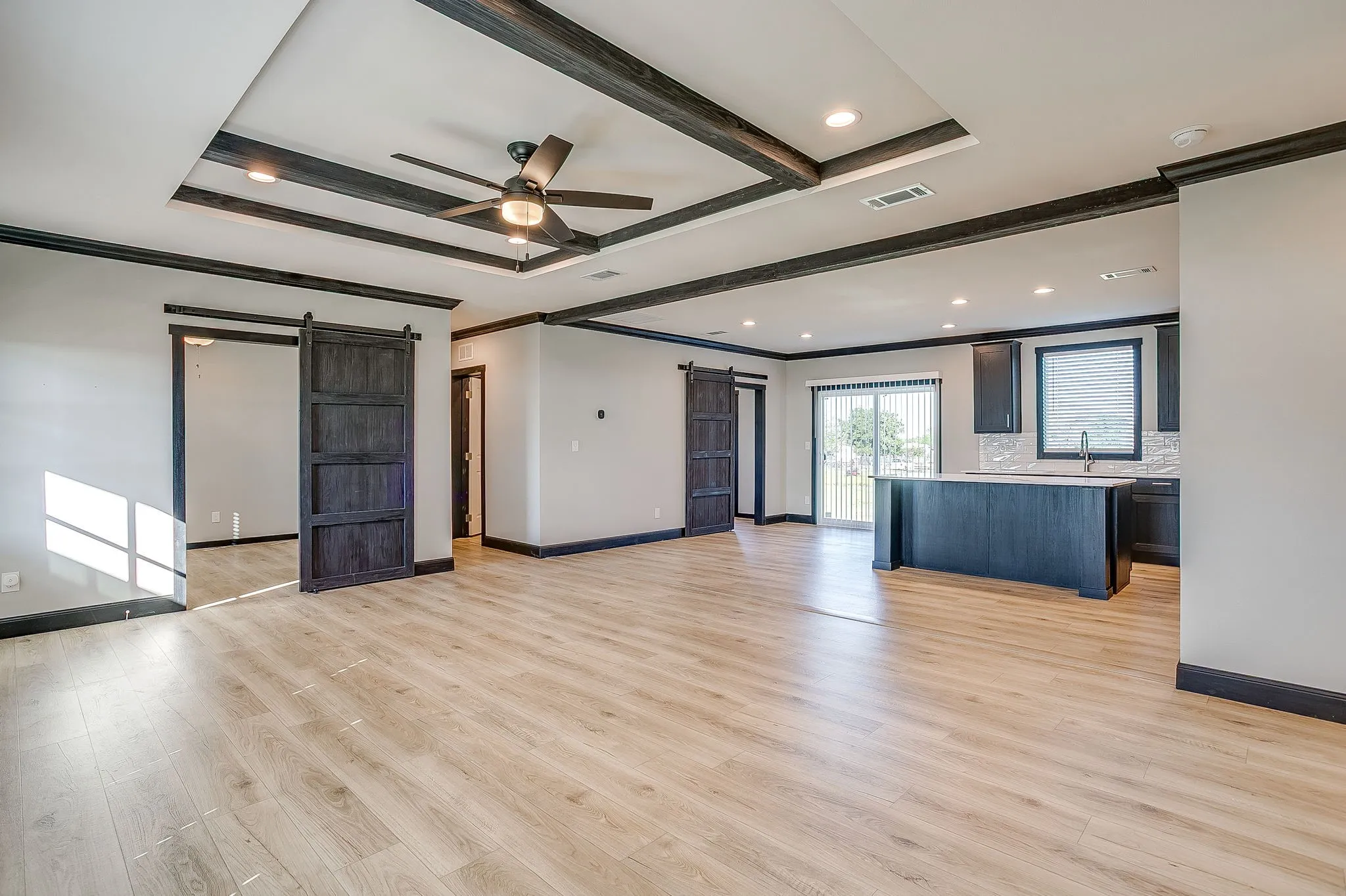 Recessed lighting and a decorative ceiling fan illuminate the light wood-finish flooring