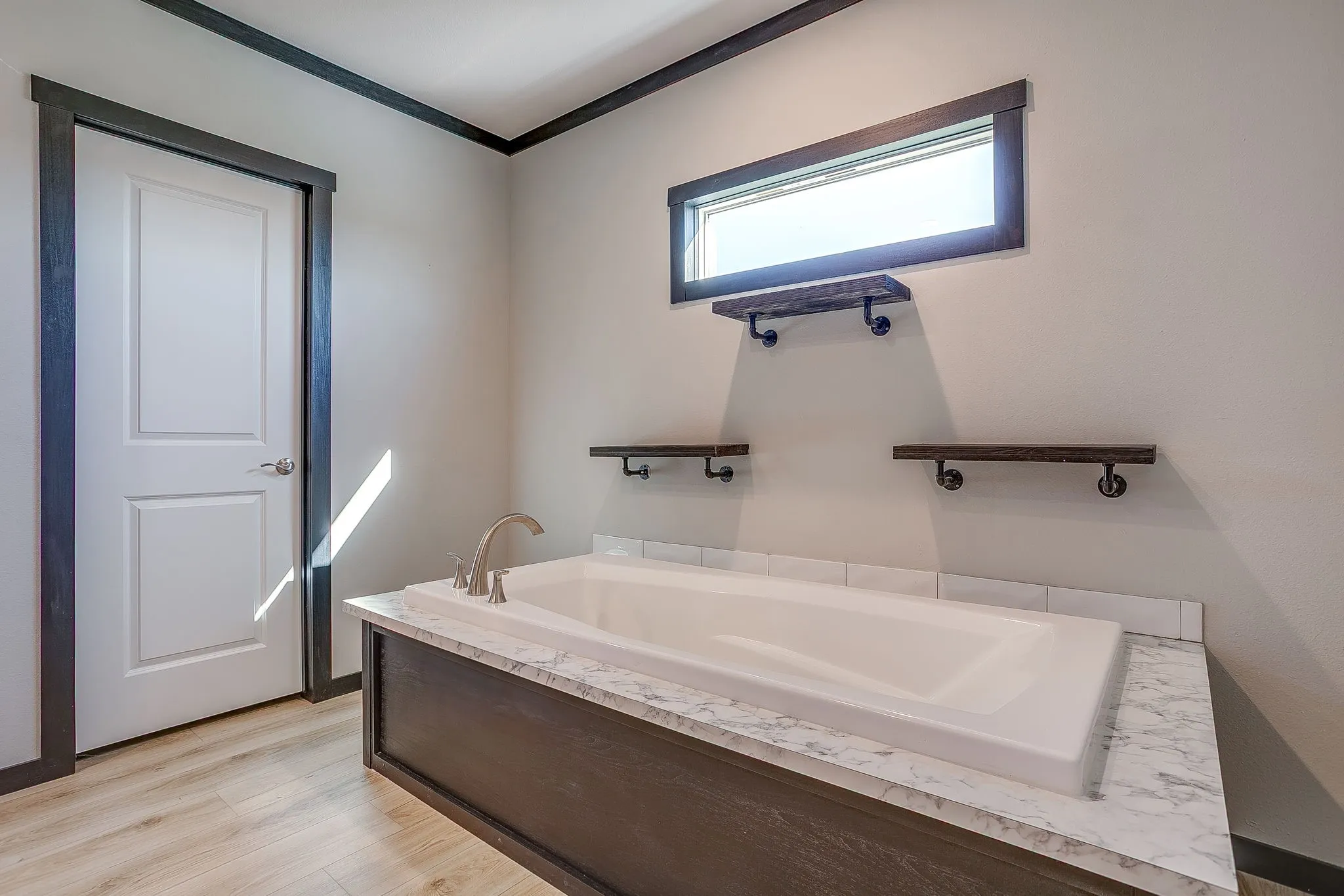 Built-in soaking tub with a stone-finish deck and wood-finish paneling