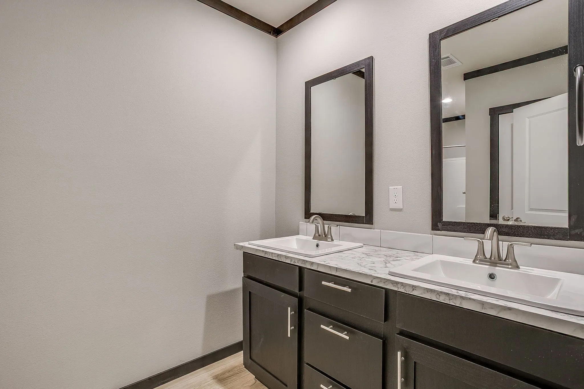 Dual vanity with integral sinks, dark wood-finish cabinetry, and brushed nickel hardware