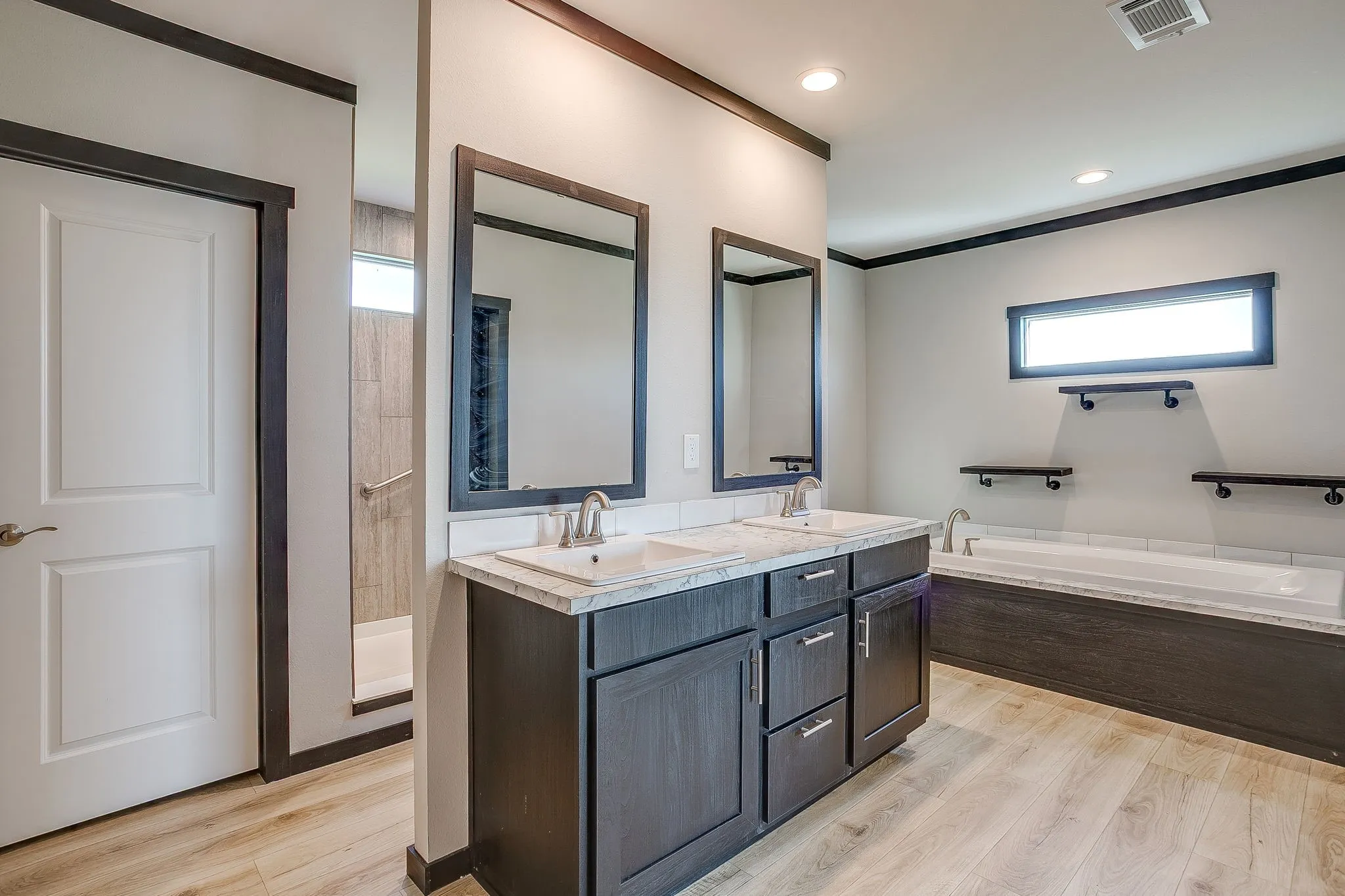 Dual vanity with integrated sinks and storage cabinetry, separate soaking tub, and walk-in shower with tile surround