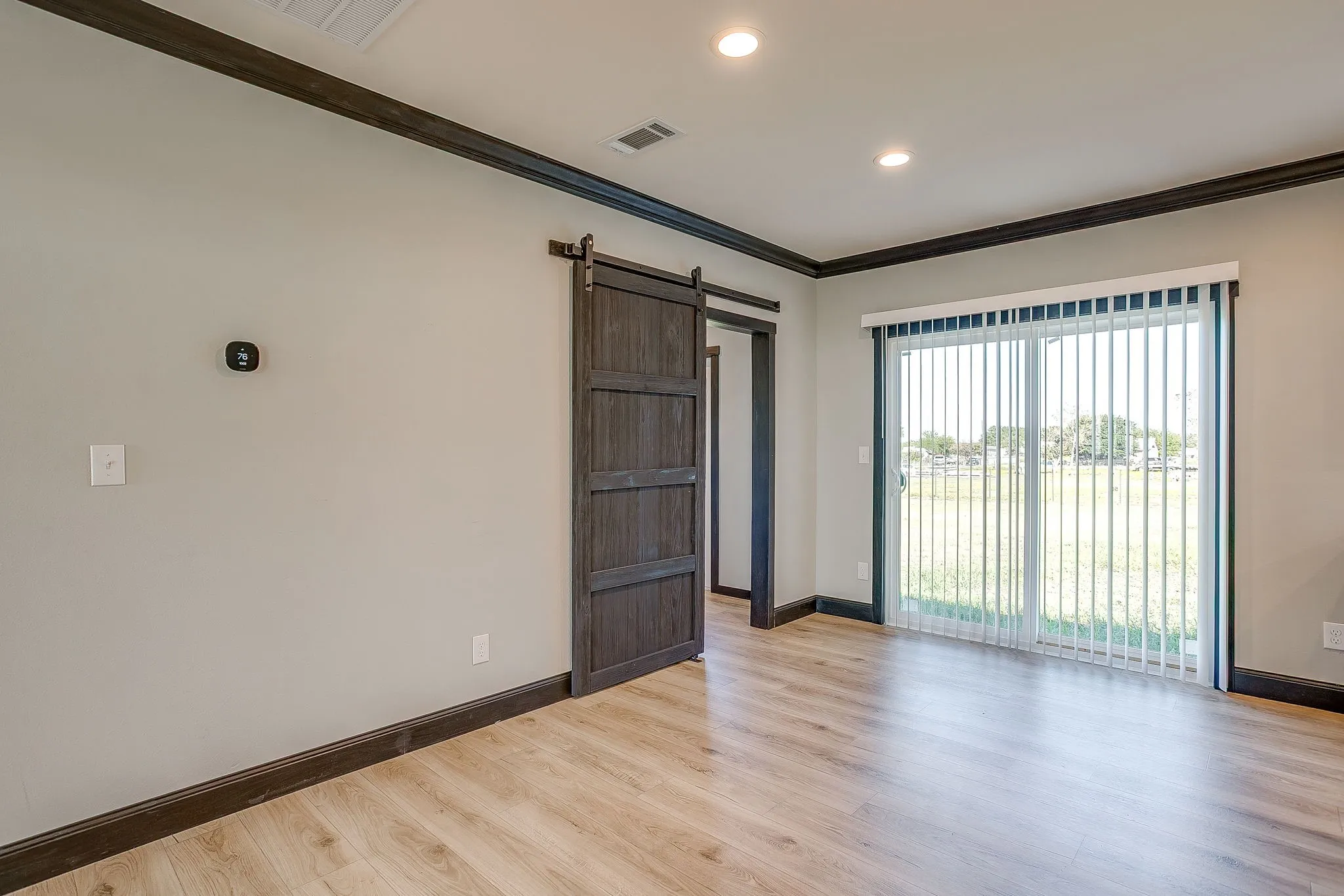Wood-finish flooring, recessed lighting, and a sliding glass door with vertical blinds
