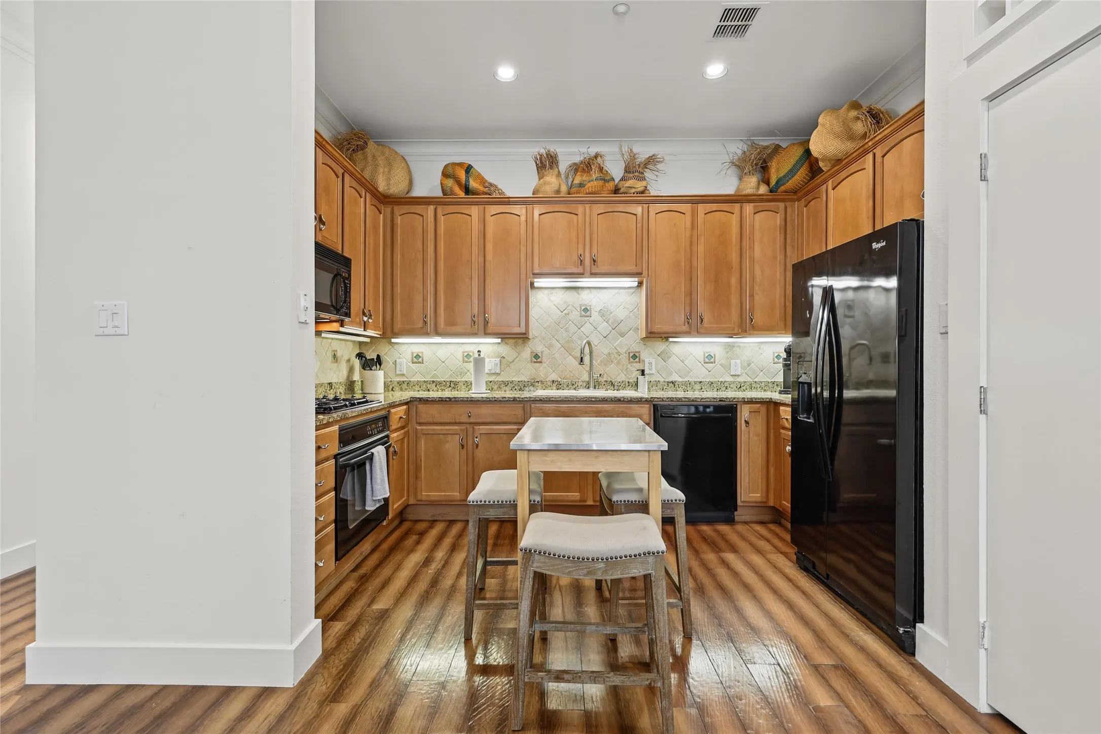 Kitchen featuring wood-finish flooring, recessed lighting, wood cabinetry, stone countertops, and a tiled backsplash