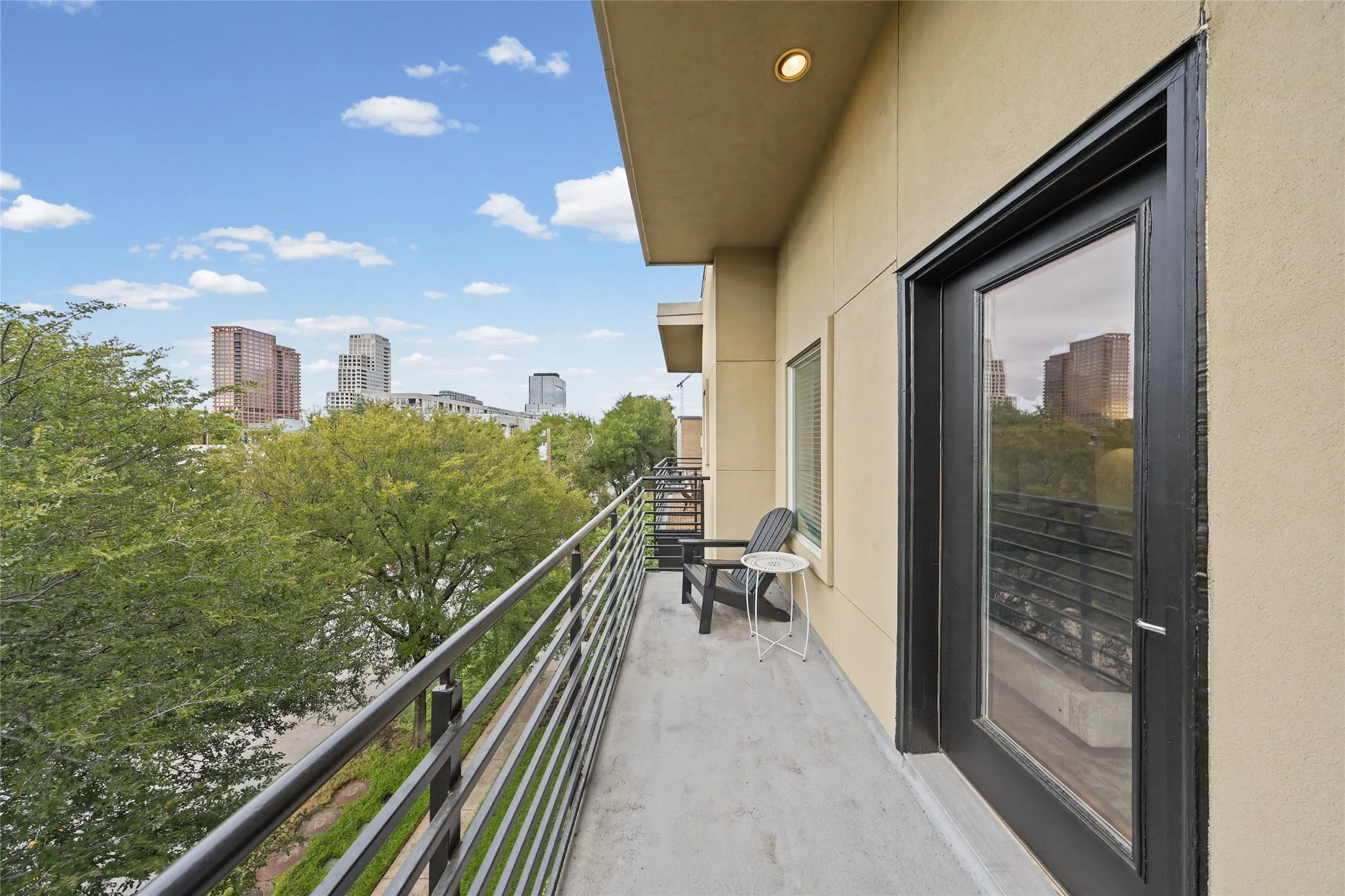 Balcony with concrete flooring and metal railings, featuring a full-light exterior door and recessed lighting