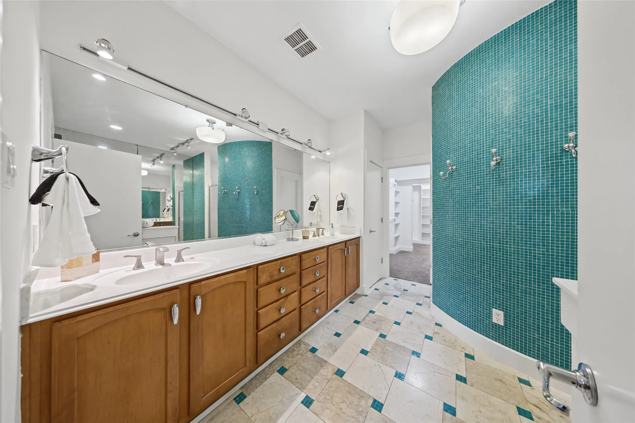 Double vanity with integrated sinks, wood cabinetry, and a large wall-mounted mirror