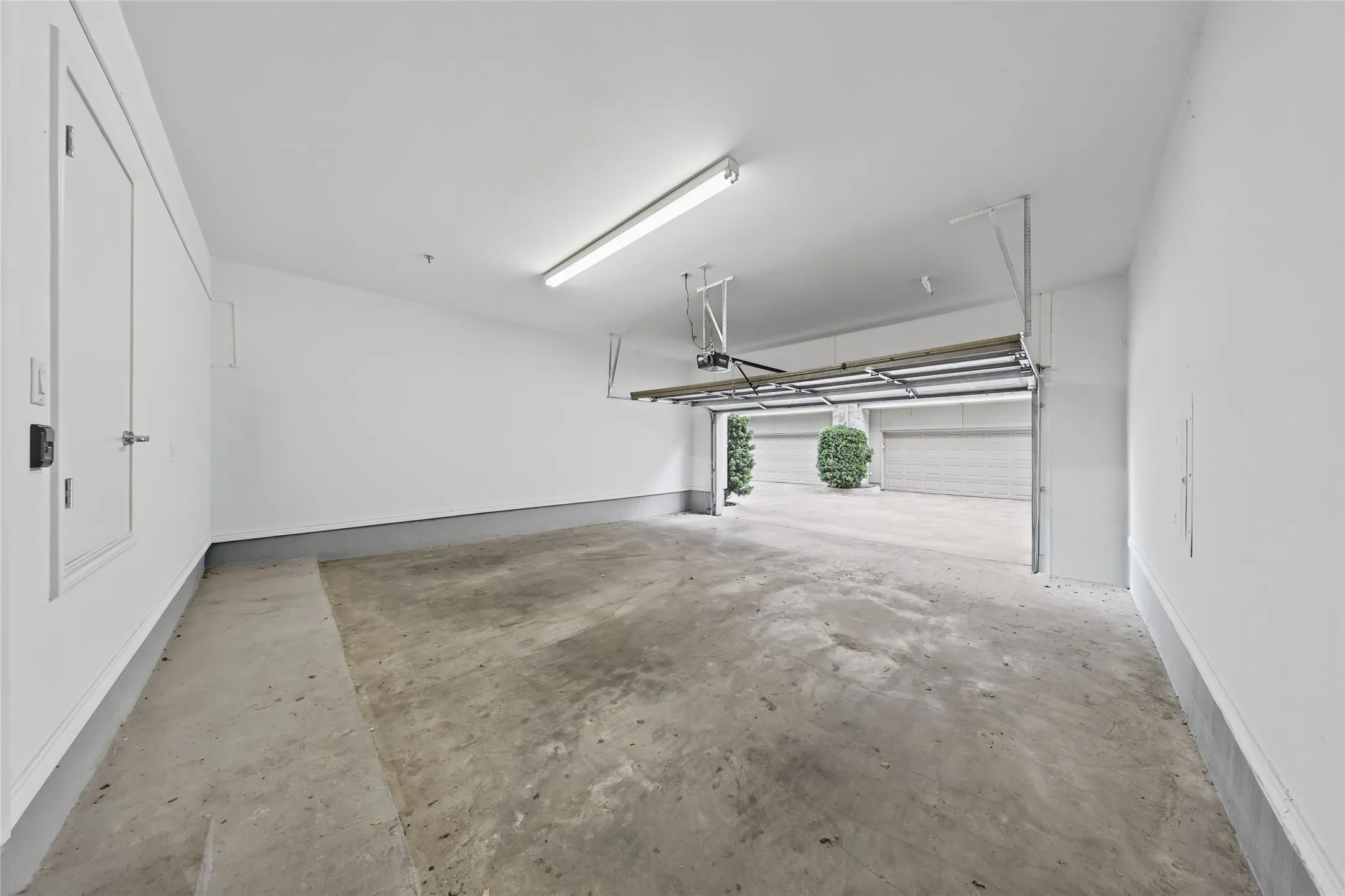 Spacious garage featuring a concrete floor, bright overhead lighting, and an automatic garage door opener mechanism