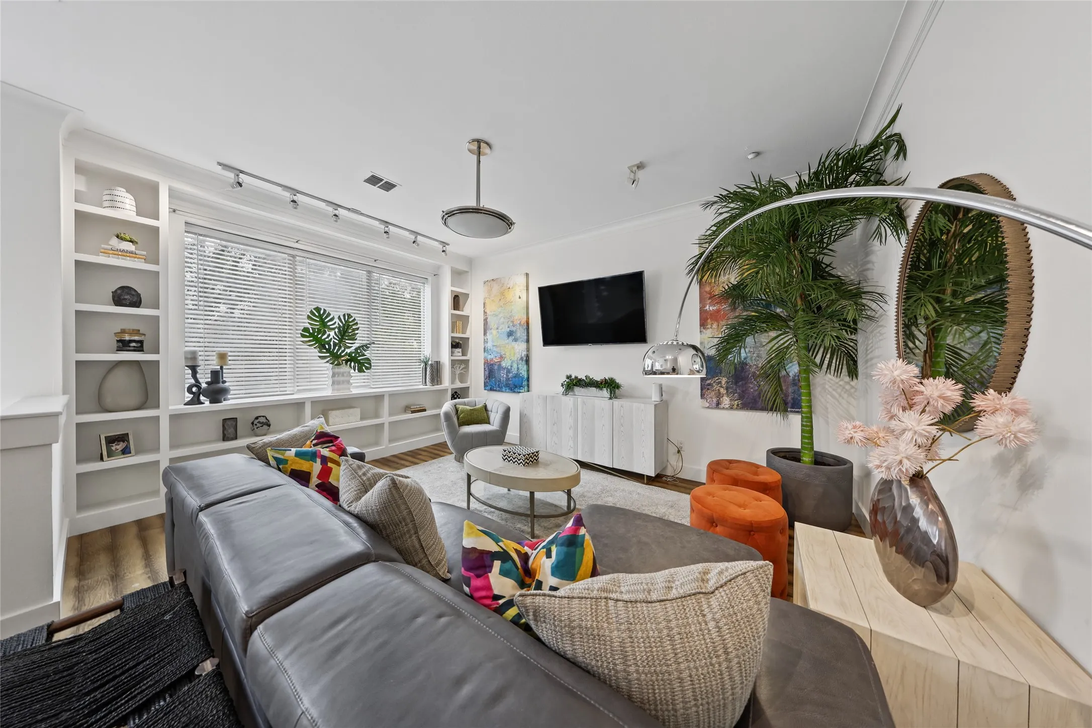 Built-in shelving flanking a large window with blinds, recessed lighting, and a modern ceiling fixture