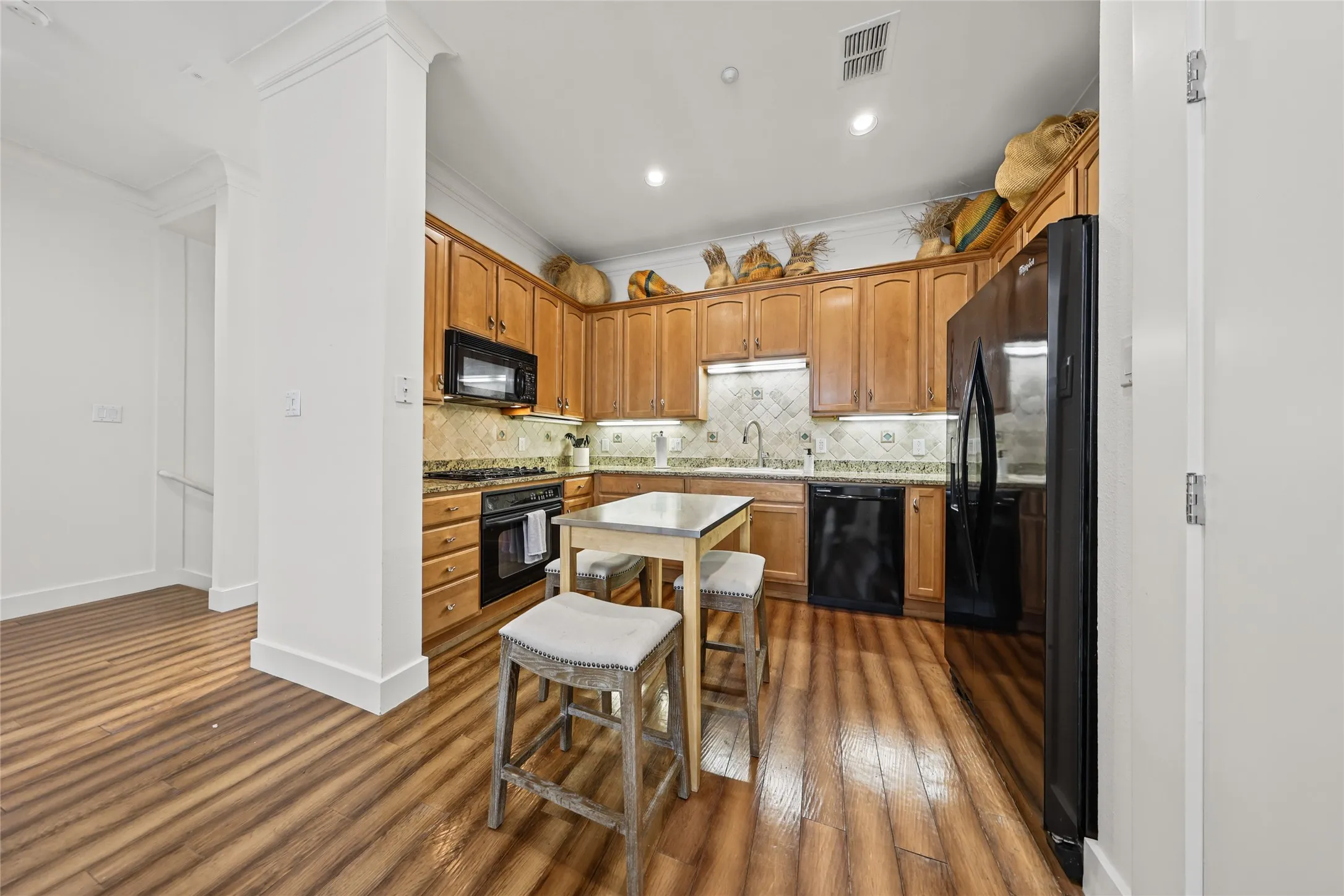 Kitchen featuring wood-finish flooring, recessed lighting, wood cabinetry, stone countertops, and a tile backsplash