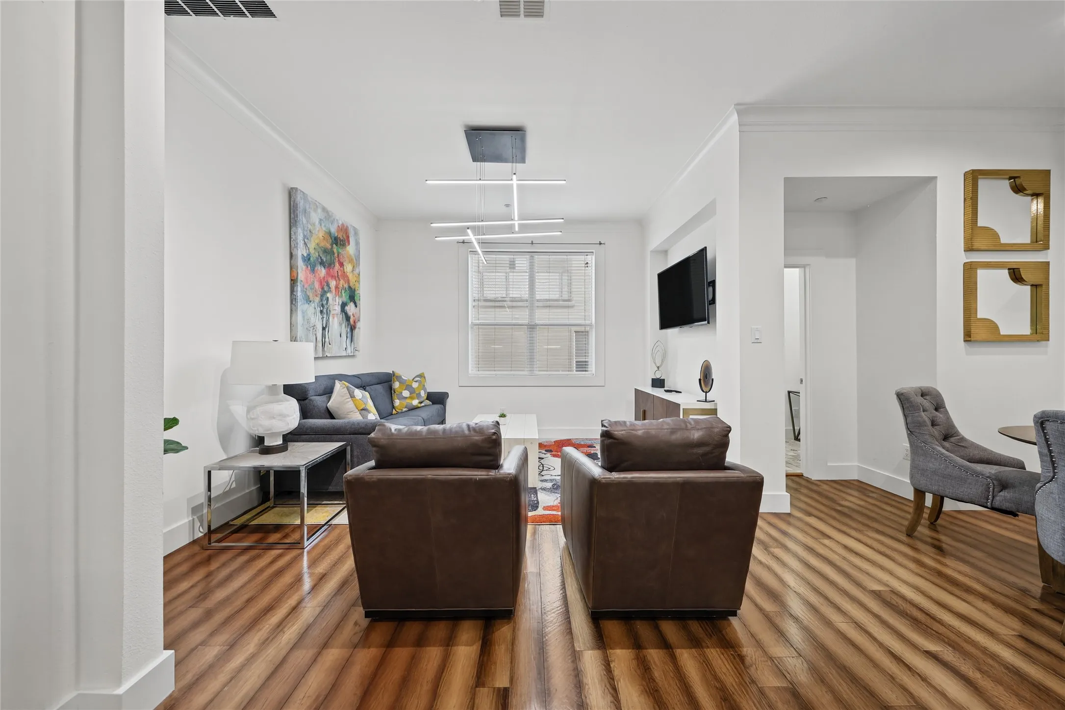 Bright, open living area showcasing hardwood flooring, recessed ceiling lighting, and large windows allowing natural light throughout