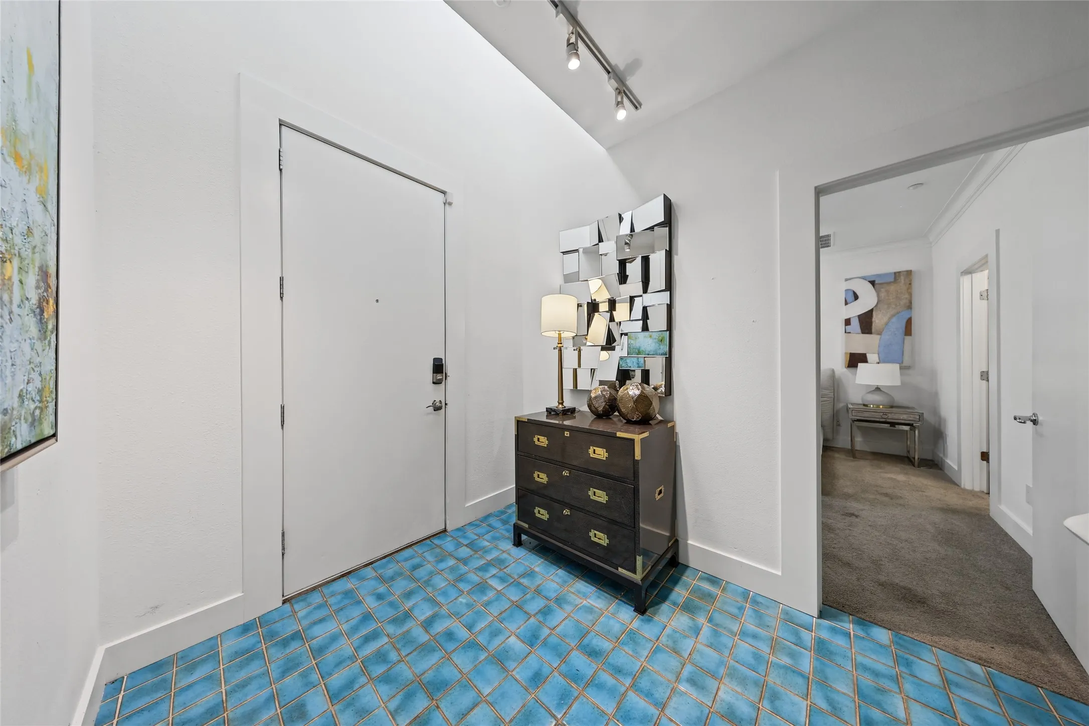 Blue tile flooring in a diamond pattern, track lighting, and a white entry door with smart lock hardware