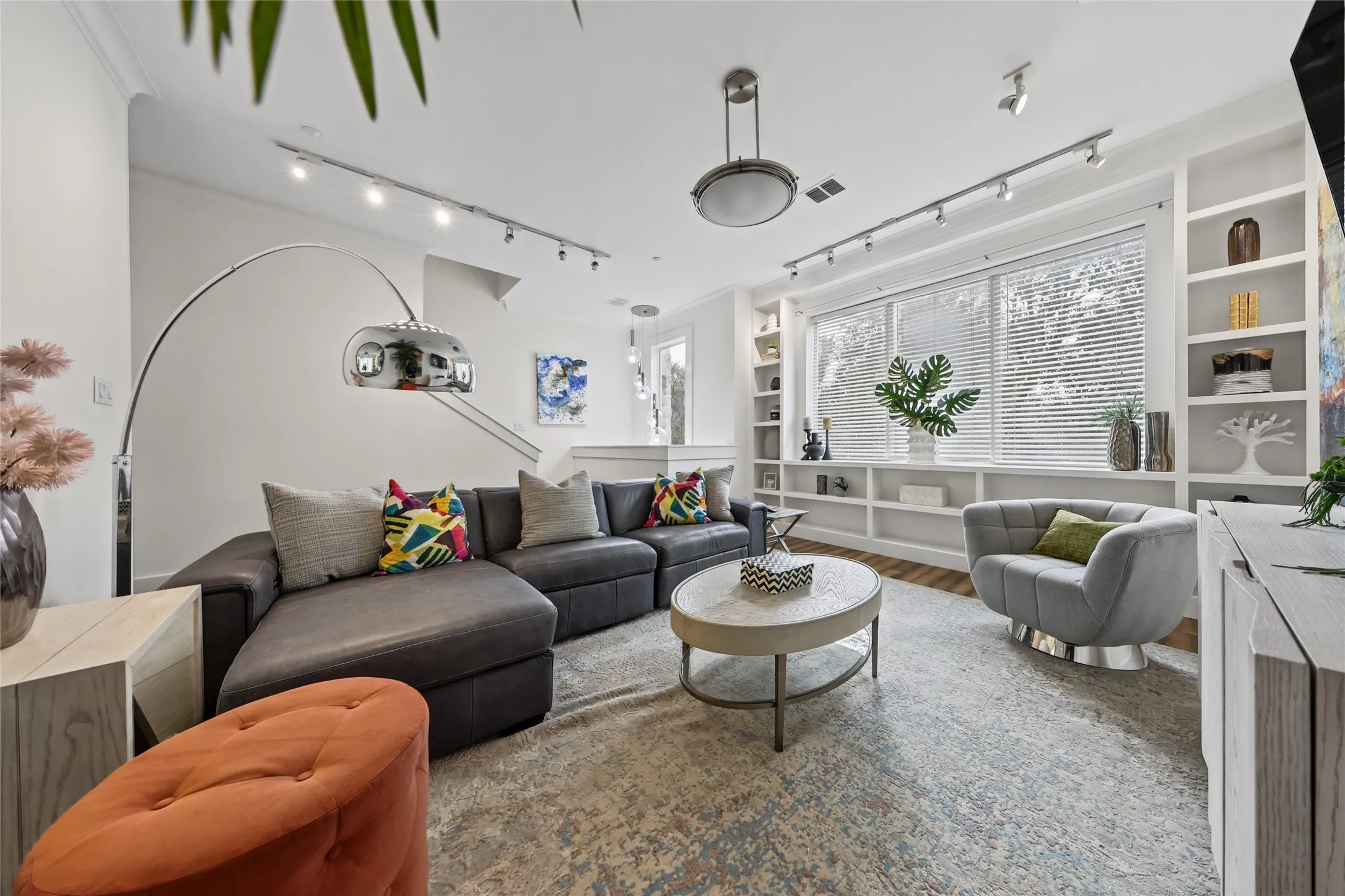 Bright living space with built-in shelving, wood-finish flooring, and recessed ceiling lighting