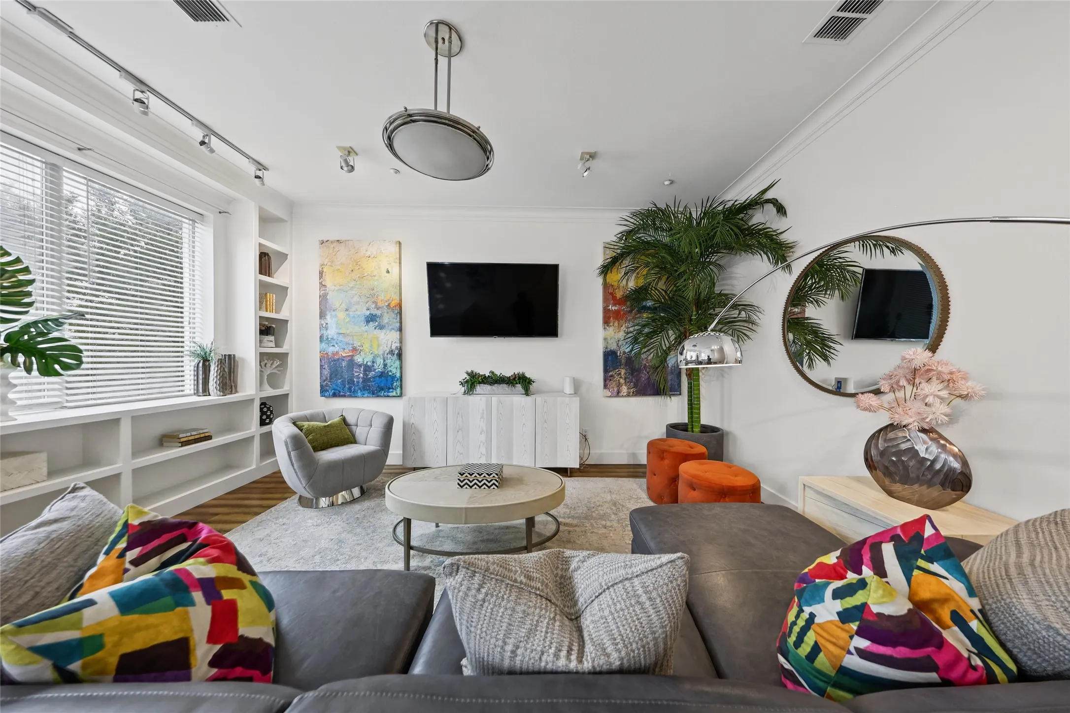 Living space featuring wood-finish flooring, built-in shelving, a large window with blinds, recessed lighting, and crown molding