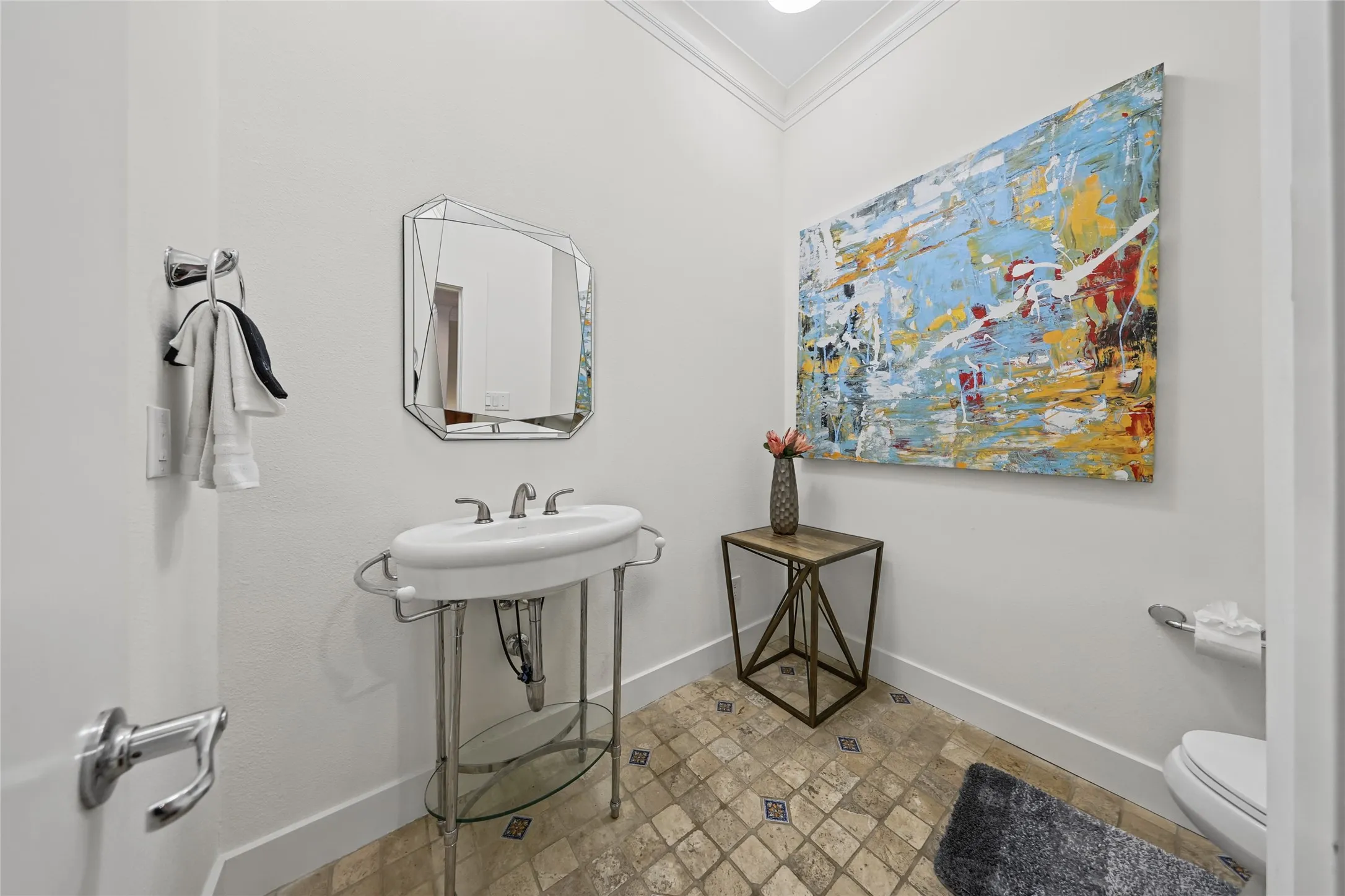 Pedestal sink with chrome fixtures and an octagonal mirror