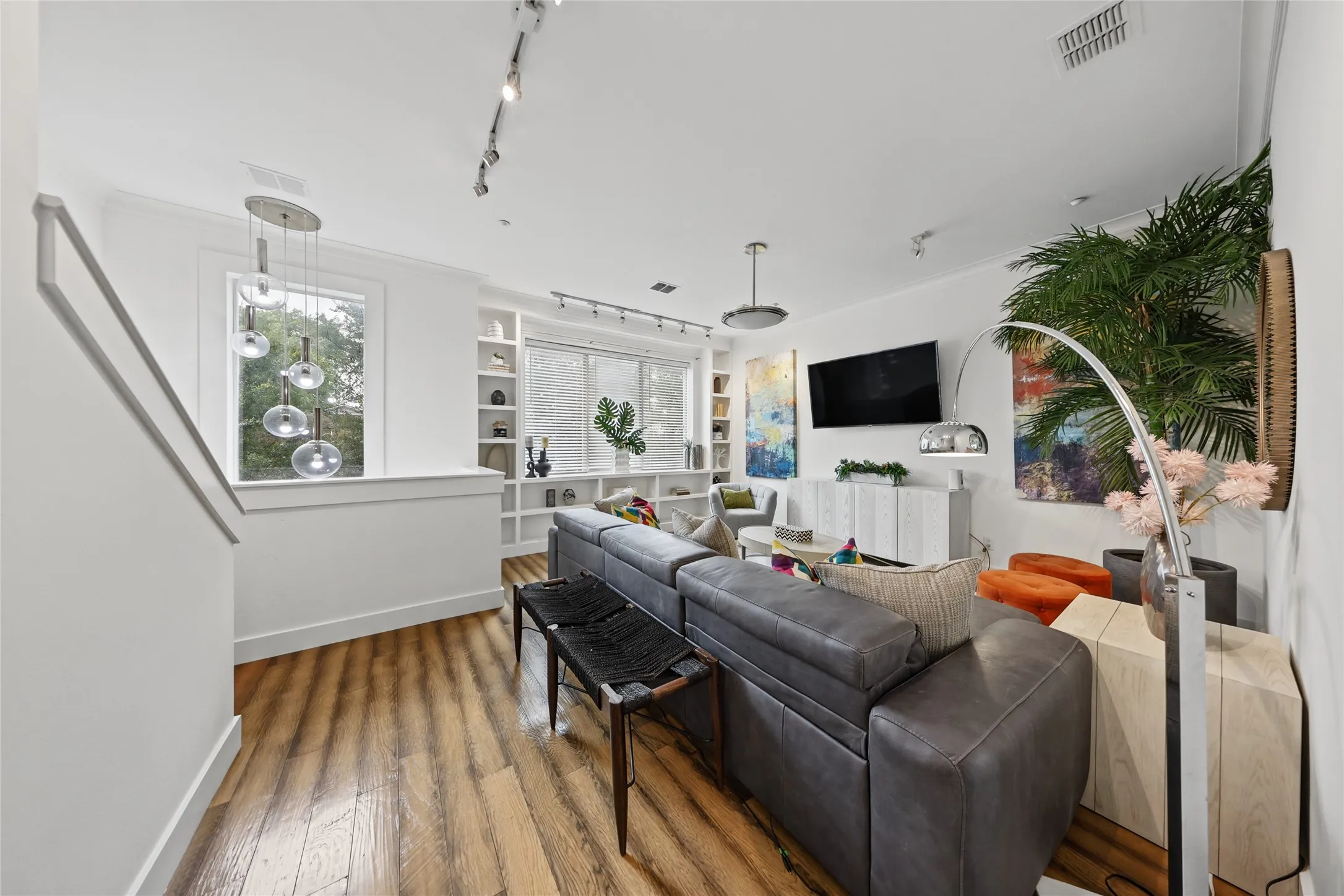 Wood-finish flooring, built-in shelving, white walls, and track lighting