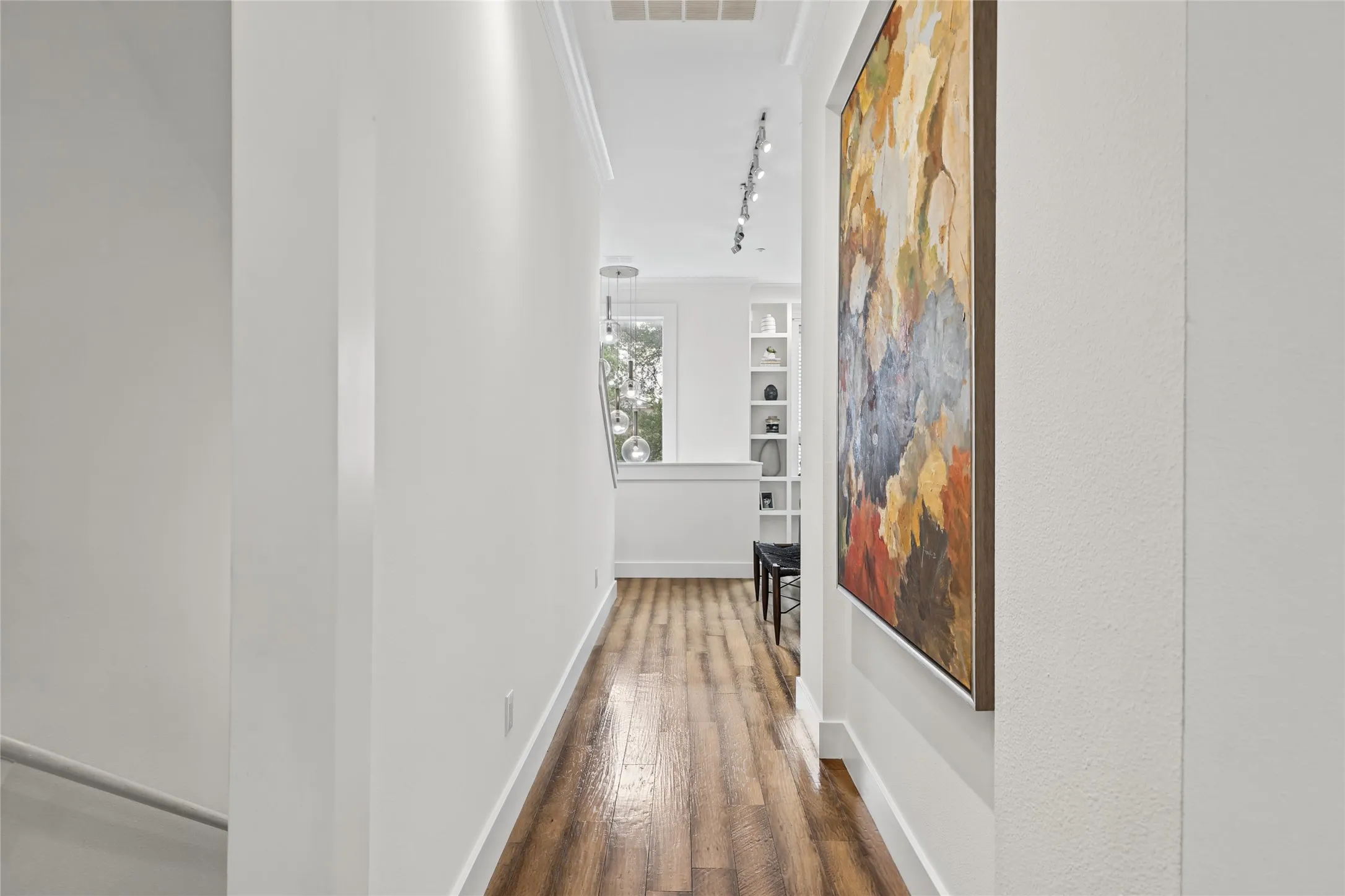 Wood-finish flooring with white baseboards, crown molding, built-in shelving, and recessed lighting