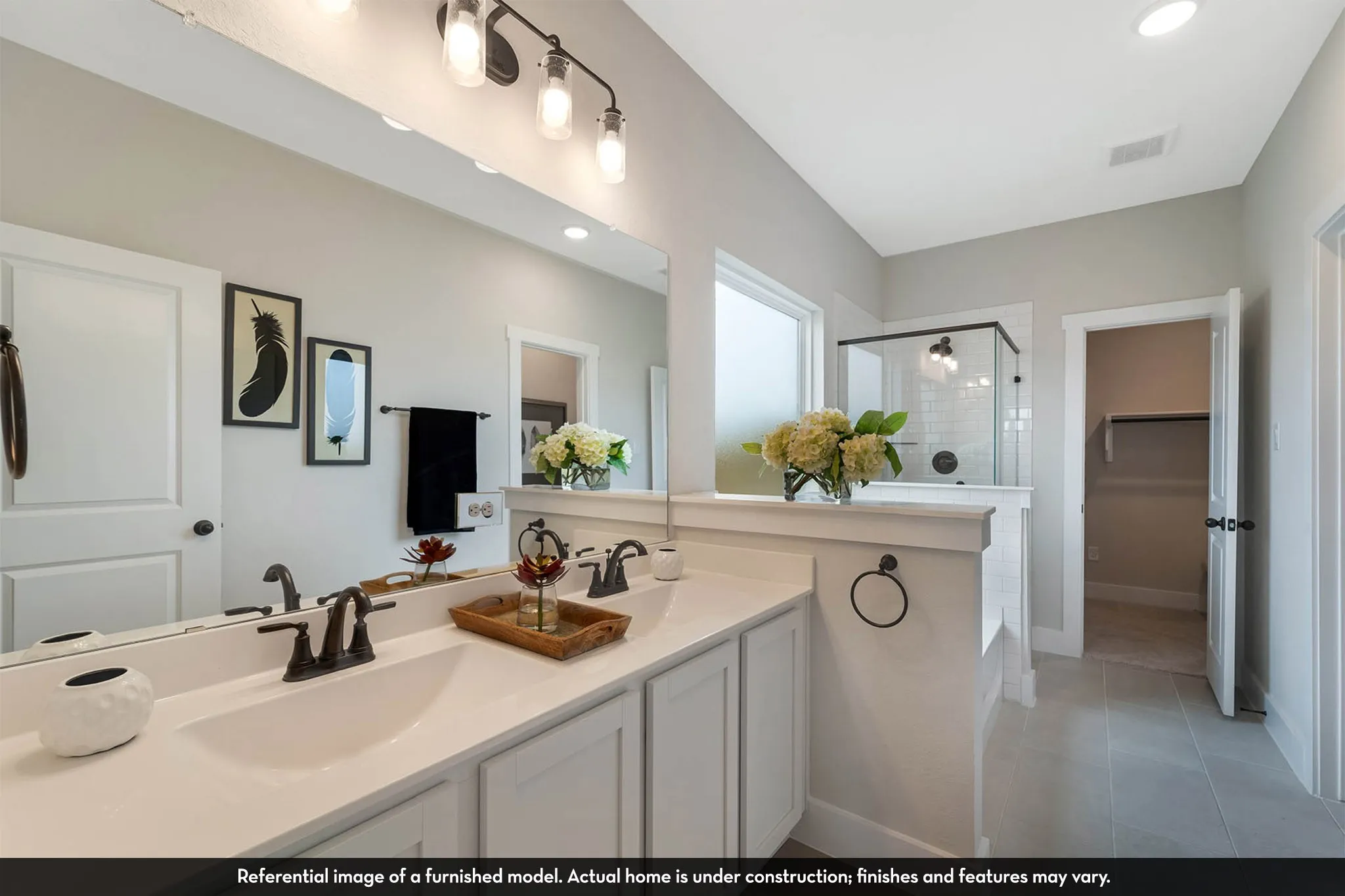 Dual undermount sinks with black hardware, an expansive vanity mirror, and recessed lighting