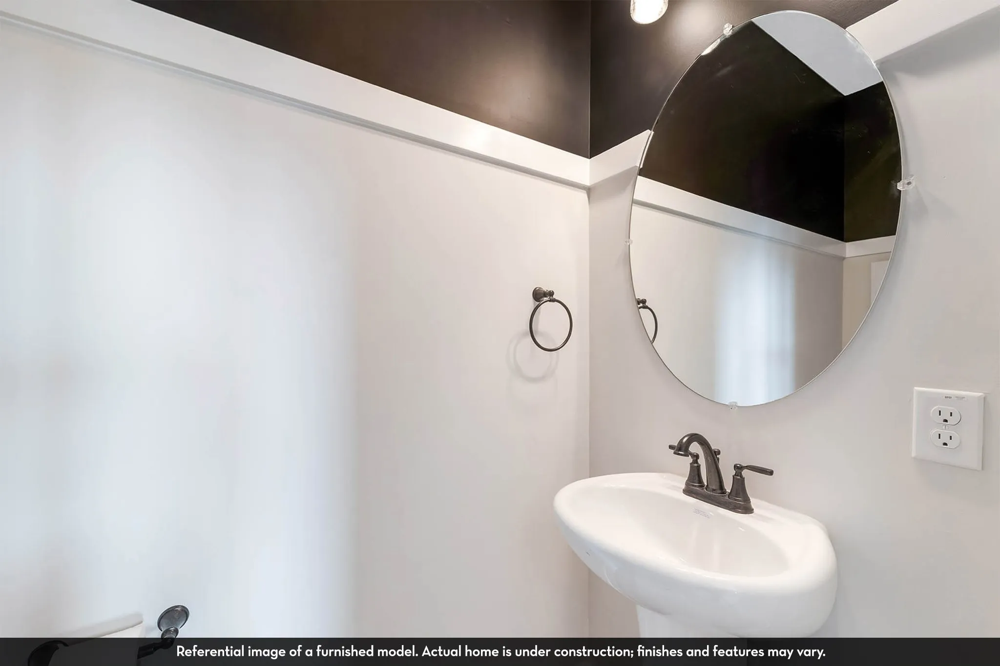 Pedestal sink with dark-toned faucet, oval mirror, and wall-mounted towel ring