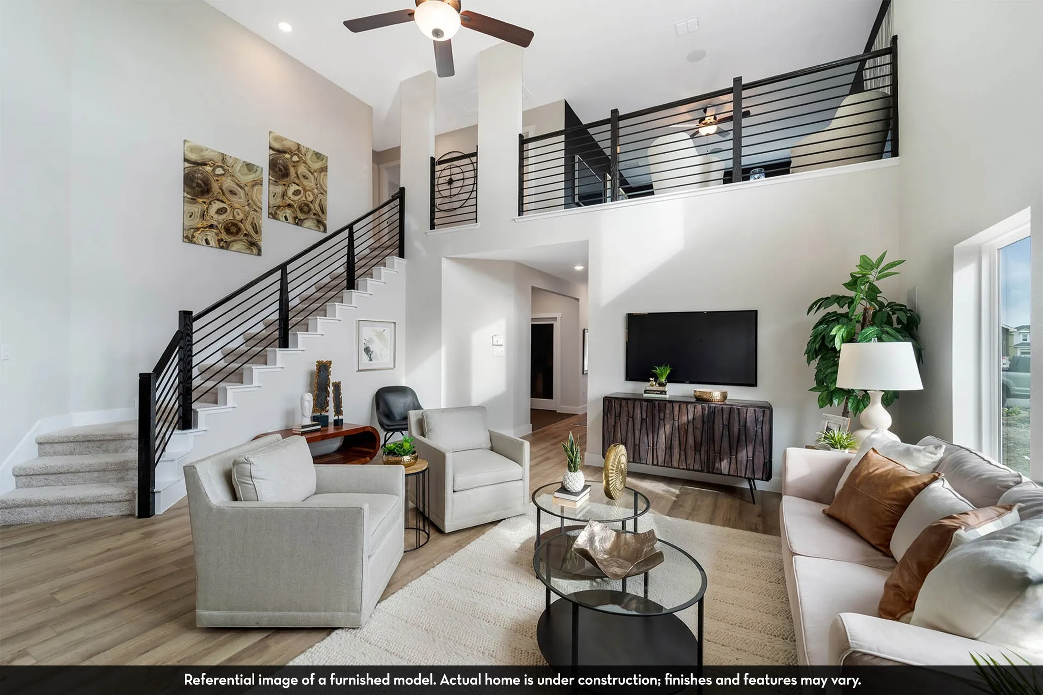 Two-story living area featuring wood-finish flooring, a contemporary staircase with black railing, and a second-story open balcony overlooking the space
