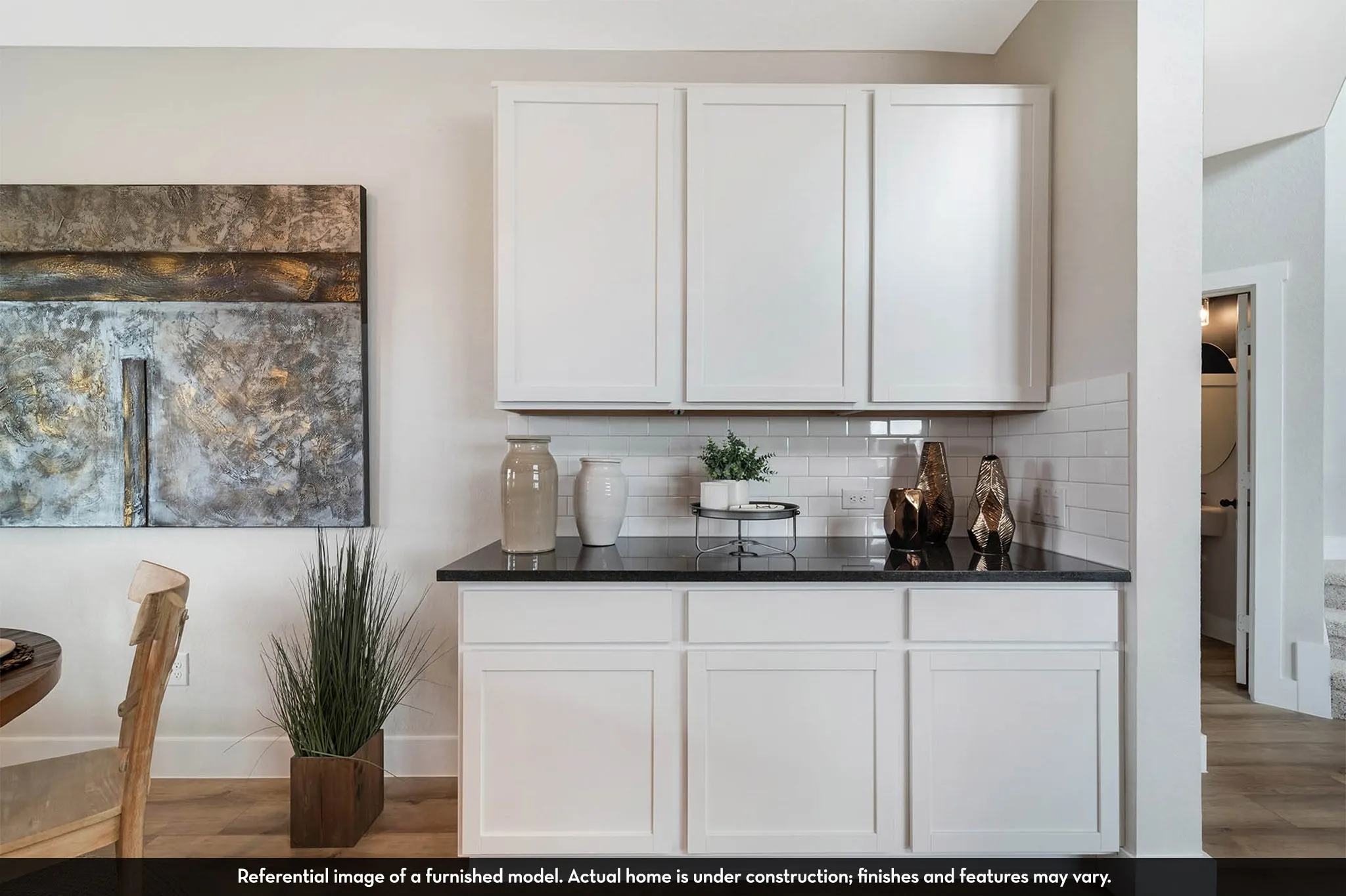 White shaker-style cabinetry, dark countertop, subway tile backsplash, light wood-finish flooring, and neutral wall paint